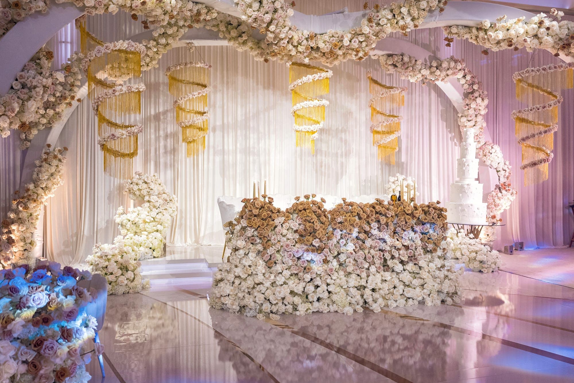 The ballroom before guests entered, ivory florals and gold draping above a mirrored floor