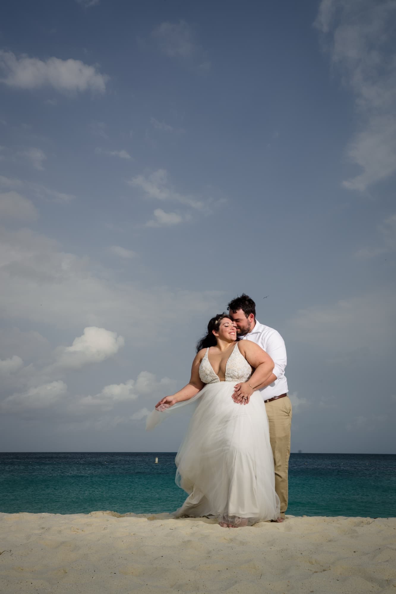 Nikole and Nick dancing on Eagle Beach with the turquoise water and a bright Aruba sky behind them