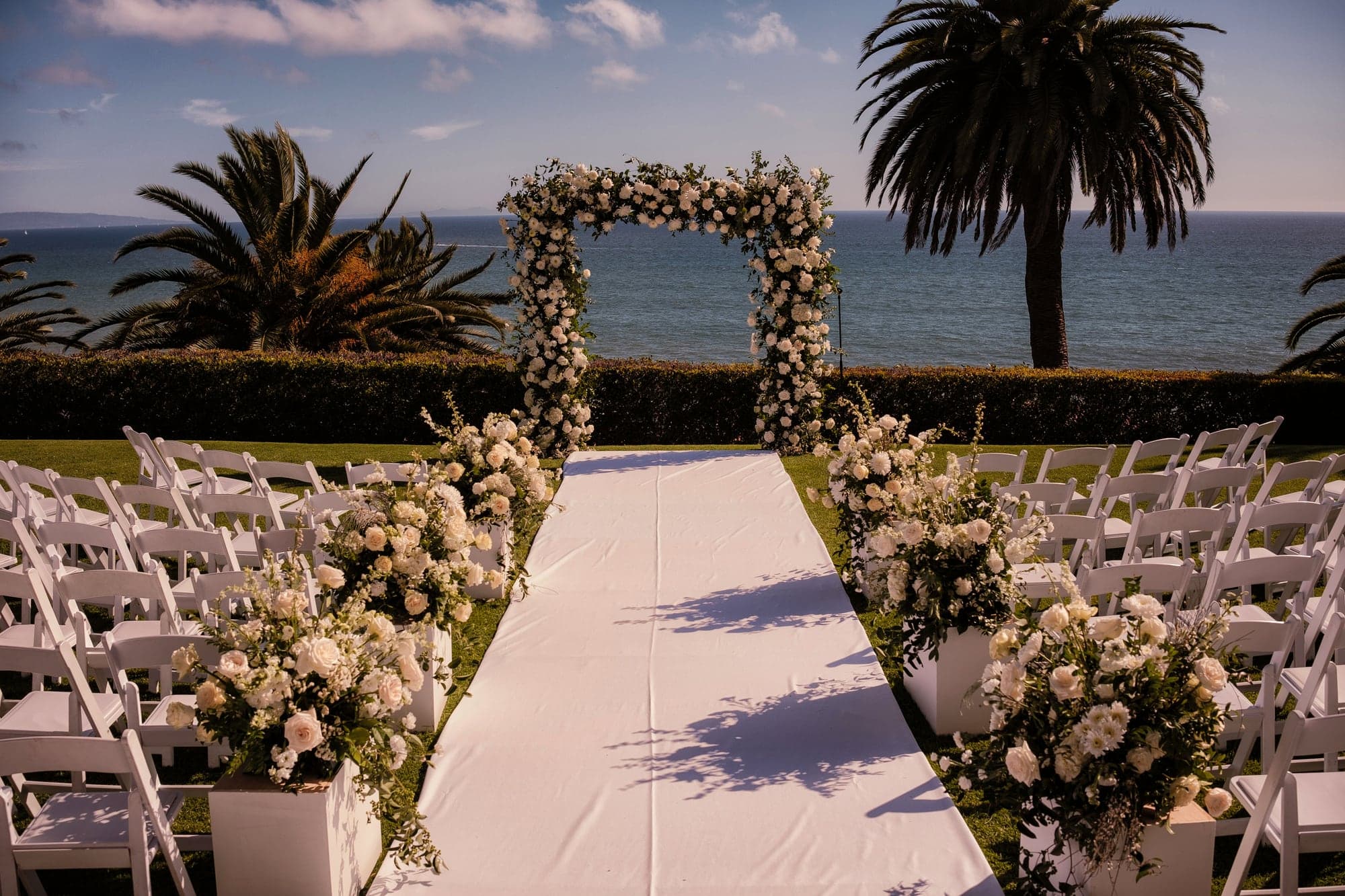White floral ceremony aisle overlooking the Pacific Ocean