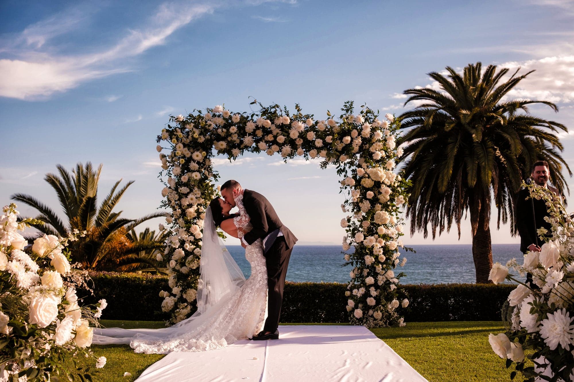 Kaitlan and James kissing beneath the ocean-view ceremony arch