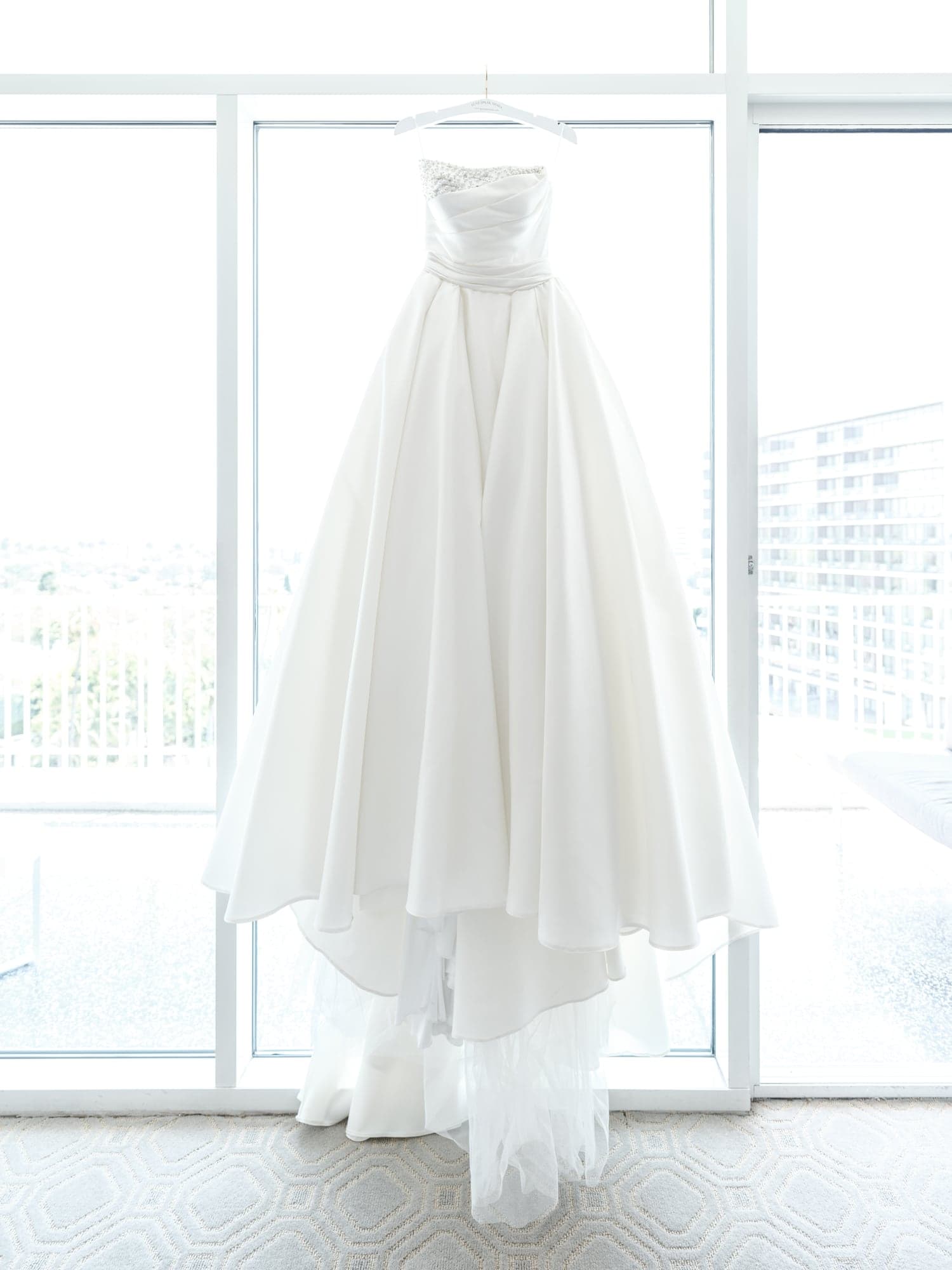 Ghazal's wedding gown hanging in bright window light at the Beverly Hilton