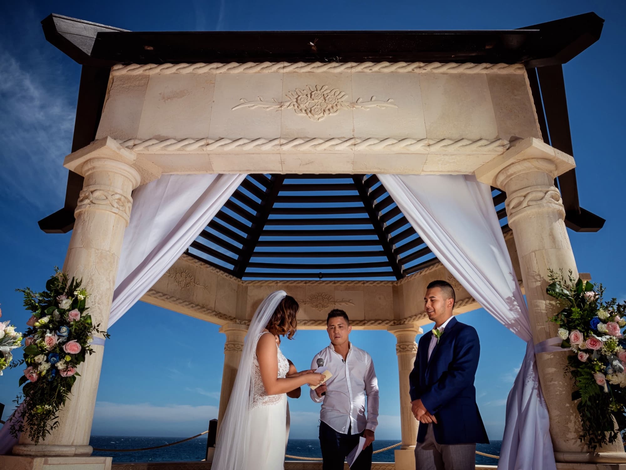 Kirsten and Jolan exchanging vows under the oceanfront stone pergola at Grand Solmar in Cabo San Lucas