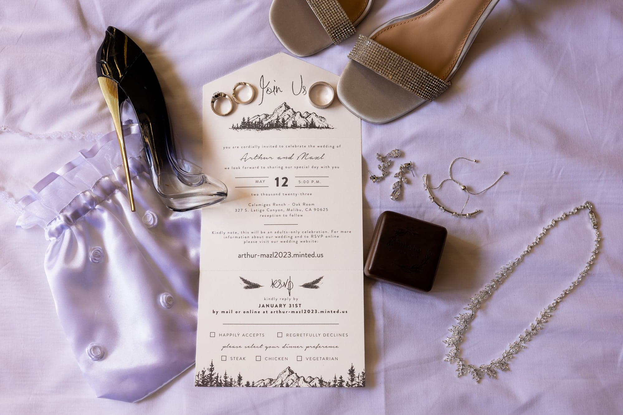 Arthur and Mazl's invitation, wedding rings, silver shoes, and jewelry arranged before the ceremony