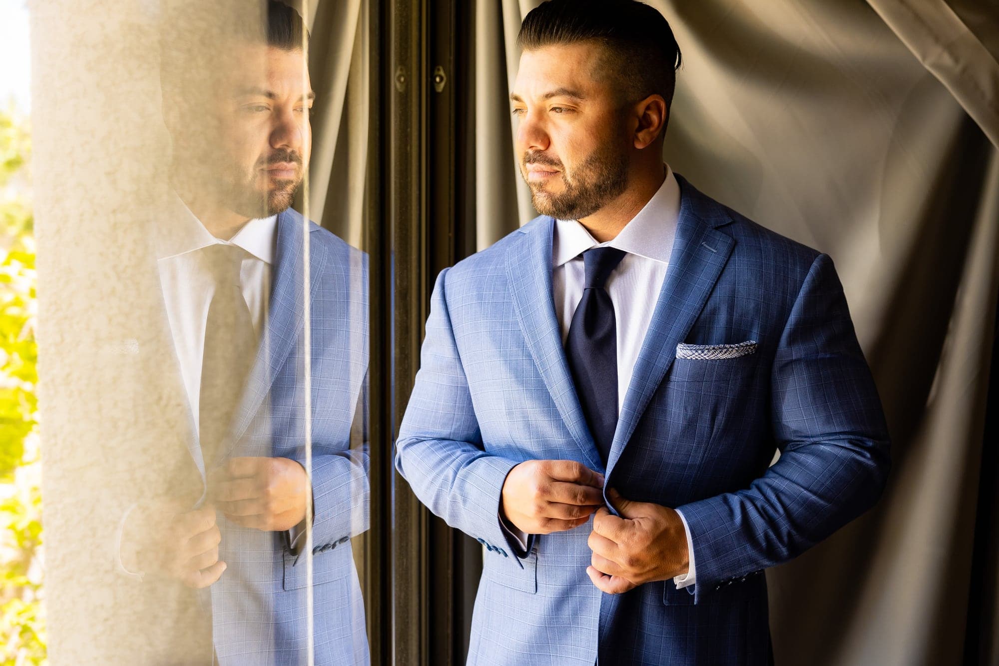 Arthur standing in his blue suit beside the Spanish-style walkways at Calamigos Ranch