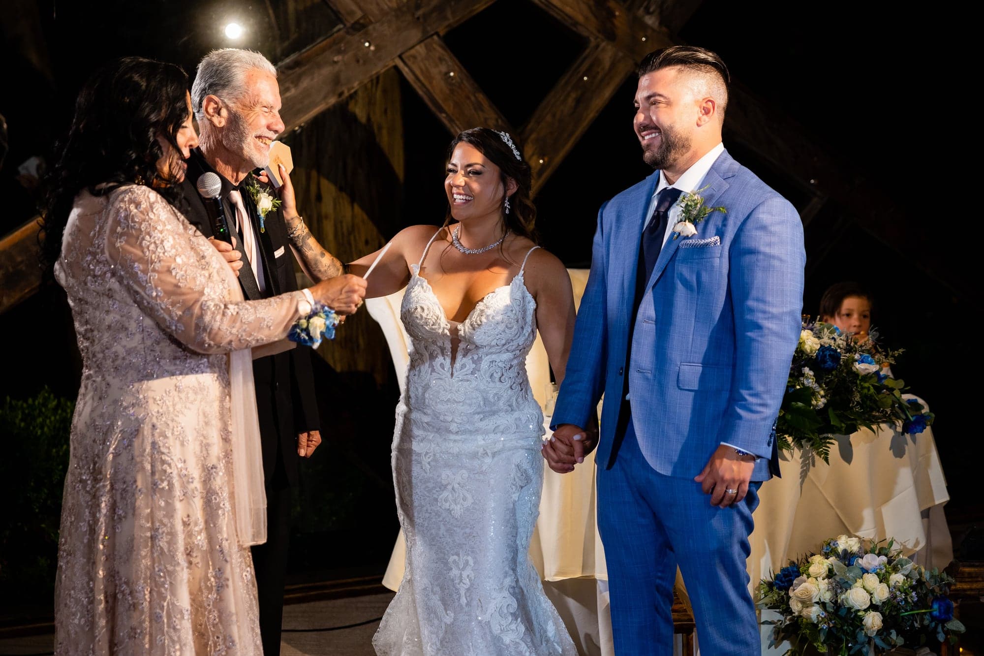 A family member giving a toast while Arthur and Mazl listen at their reception table