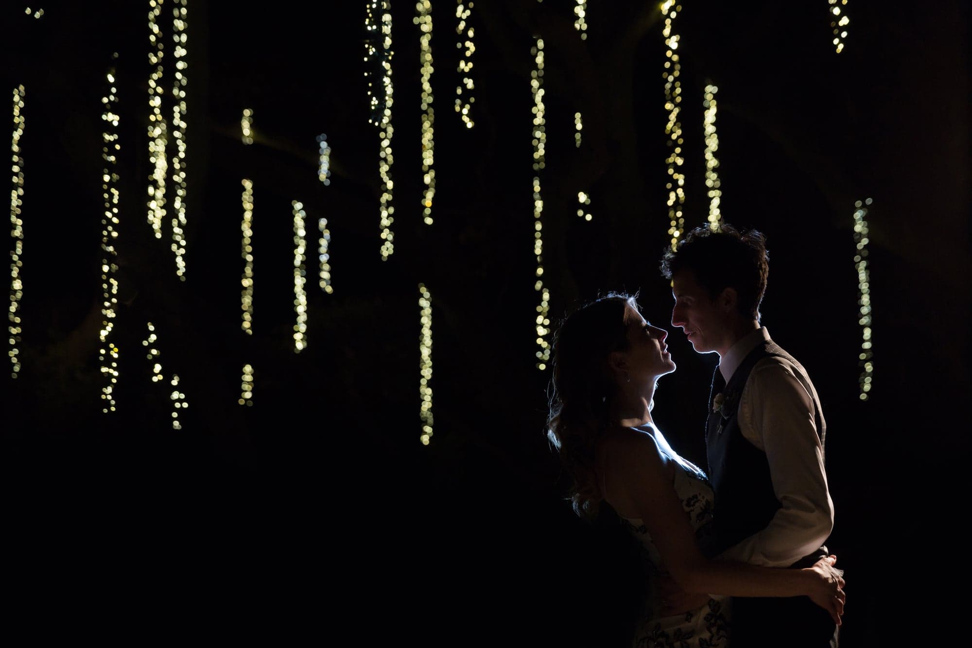 Wedding couple silhouetted beneath hanging lights at Calamigos Ranch
