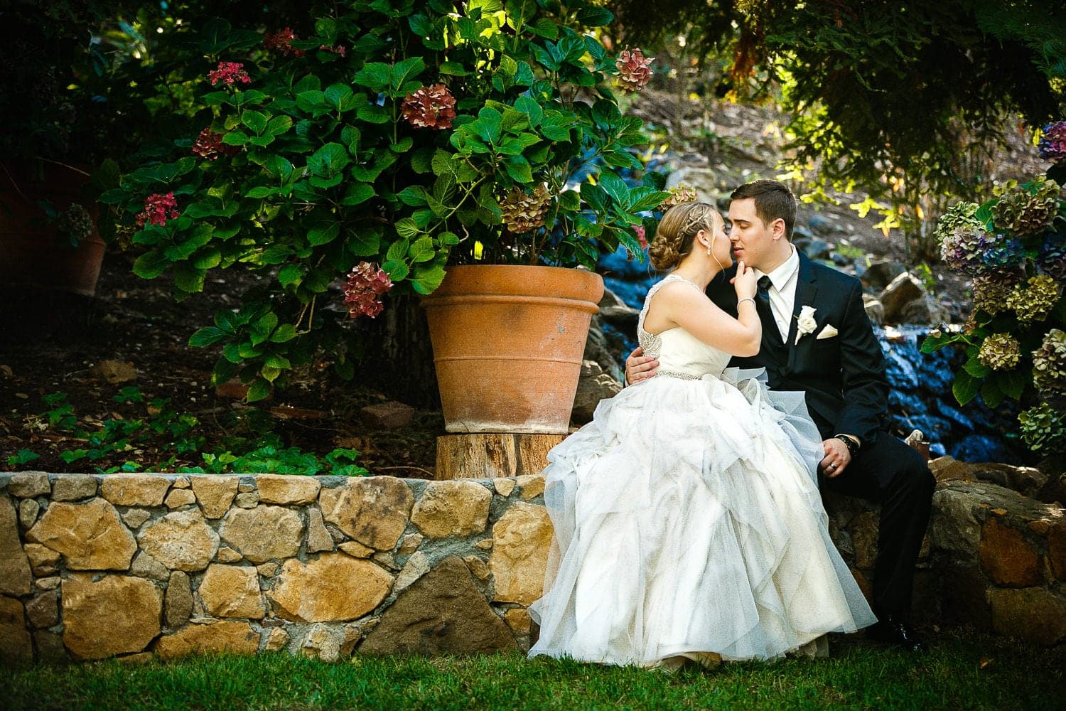 Kelly and John sharing a kiss in the Calamigos gardens