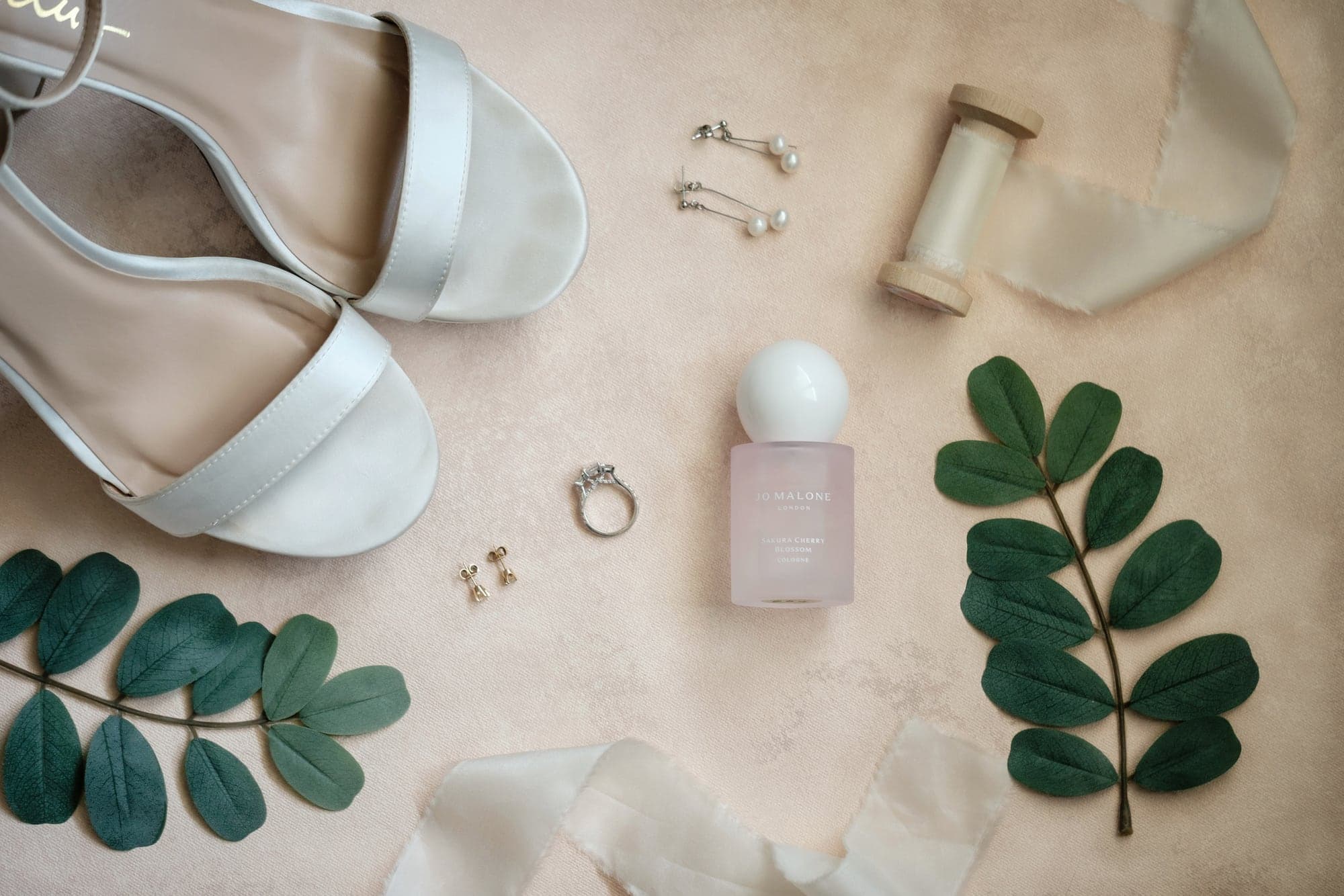 White shoes, pearl earrings, a wedding ring, and greenery arranged before the Birch Room ceremony