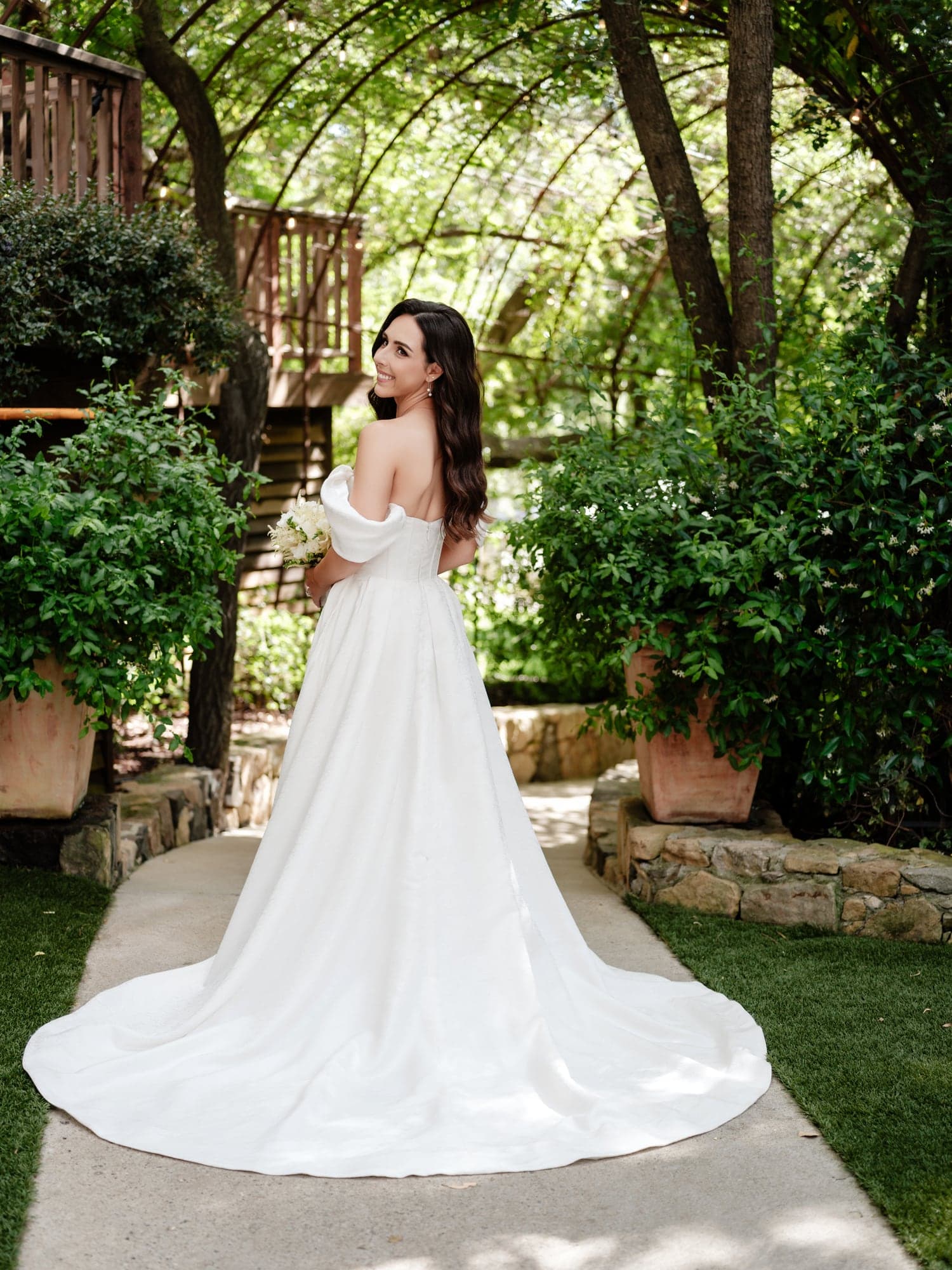 The bride standing on a garden path in her gown before the Birch Room ceremony