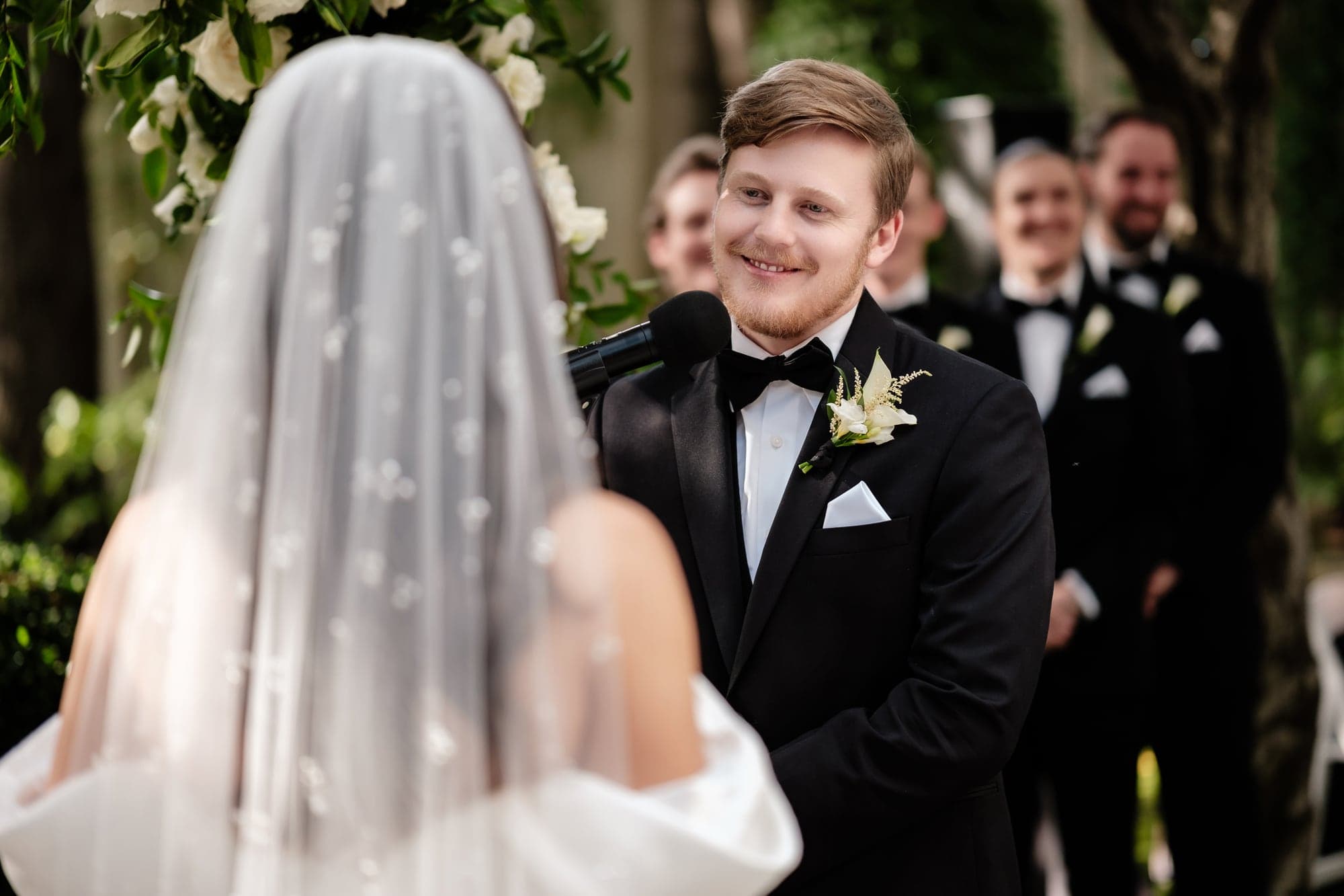 The newlyweds standing together beneath trees immediately after their Birch Room ceremony
