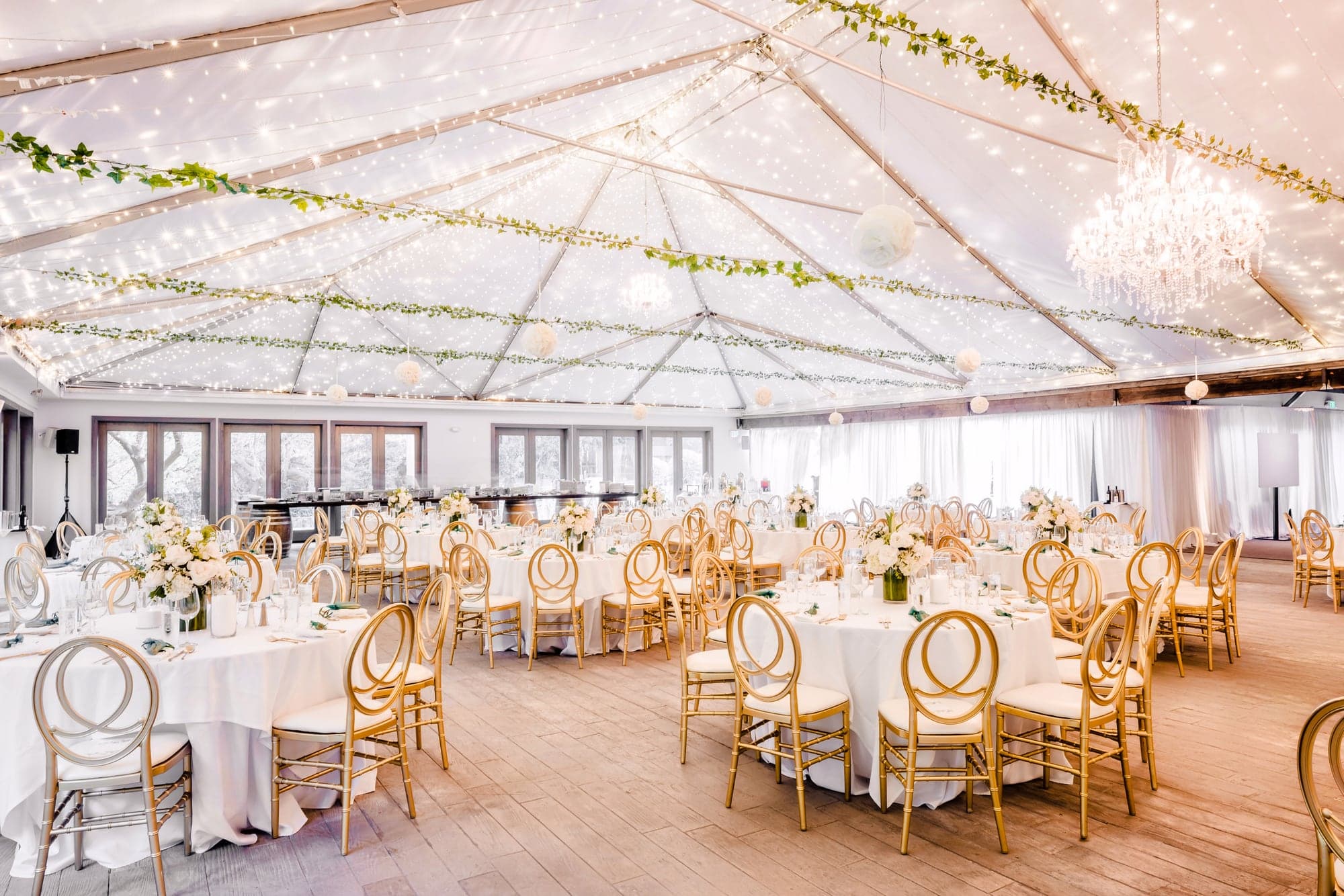 The light-filled Pavilion reception prepared with pale linens, gold chairs, and greenery