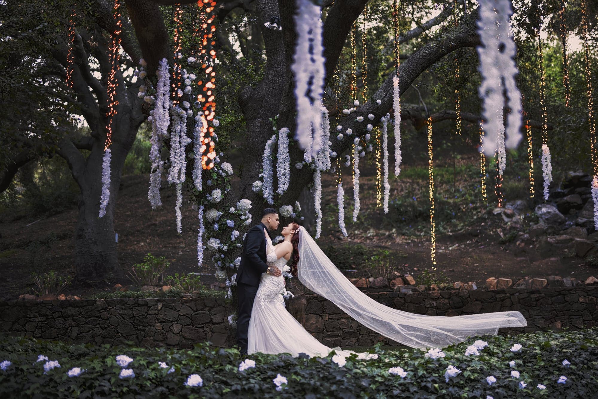 Gina and Alonso standing beneath the birch trees at Calamigos Ranch with her train extended behind them, photographed by Michael Anthony Photography