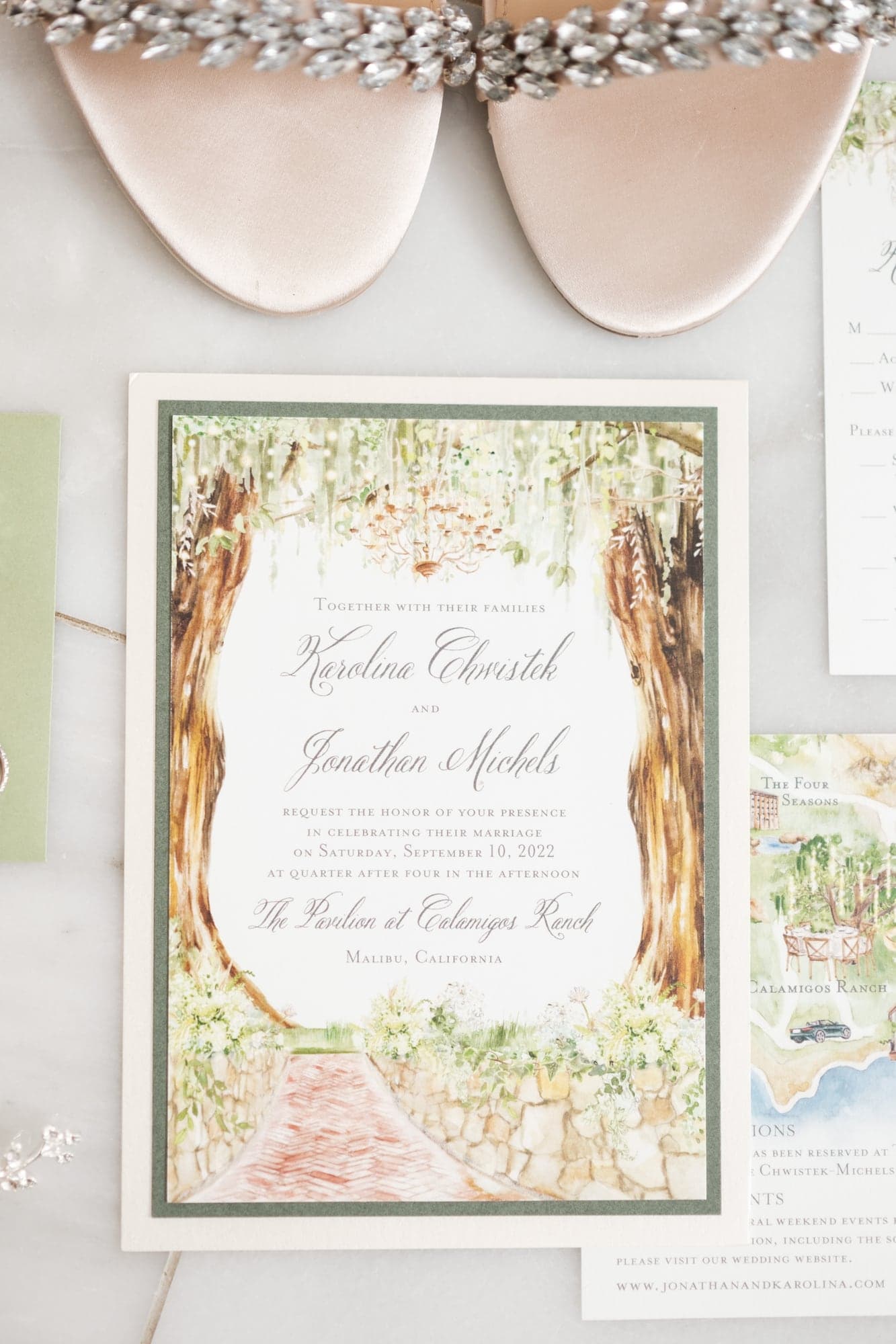 Karolina and Jonathan's pale green wedding stationery and rings arranged before the Calamigos Ranch ceremony