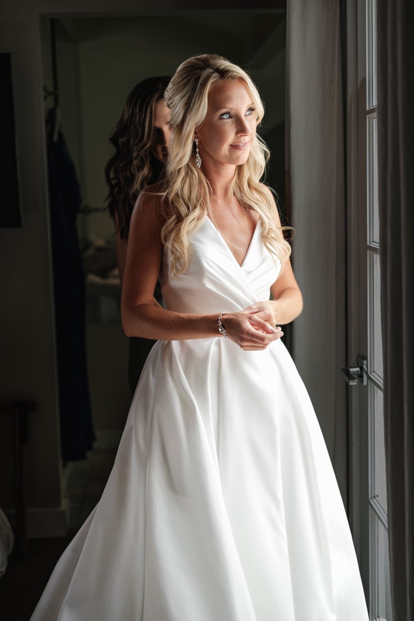 Karolina standing in dramatic window light as she prepares at Calamigos Ranch