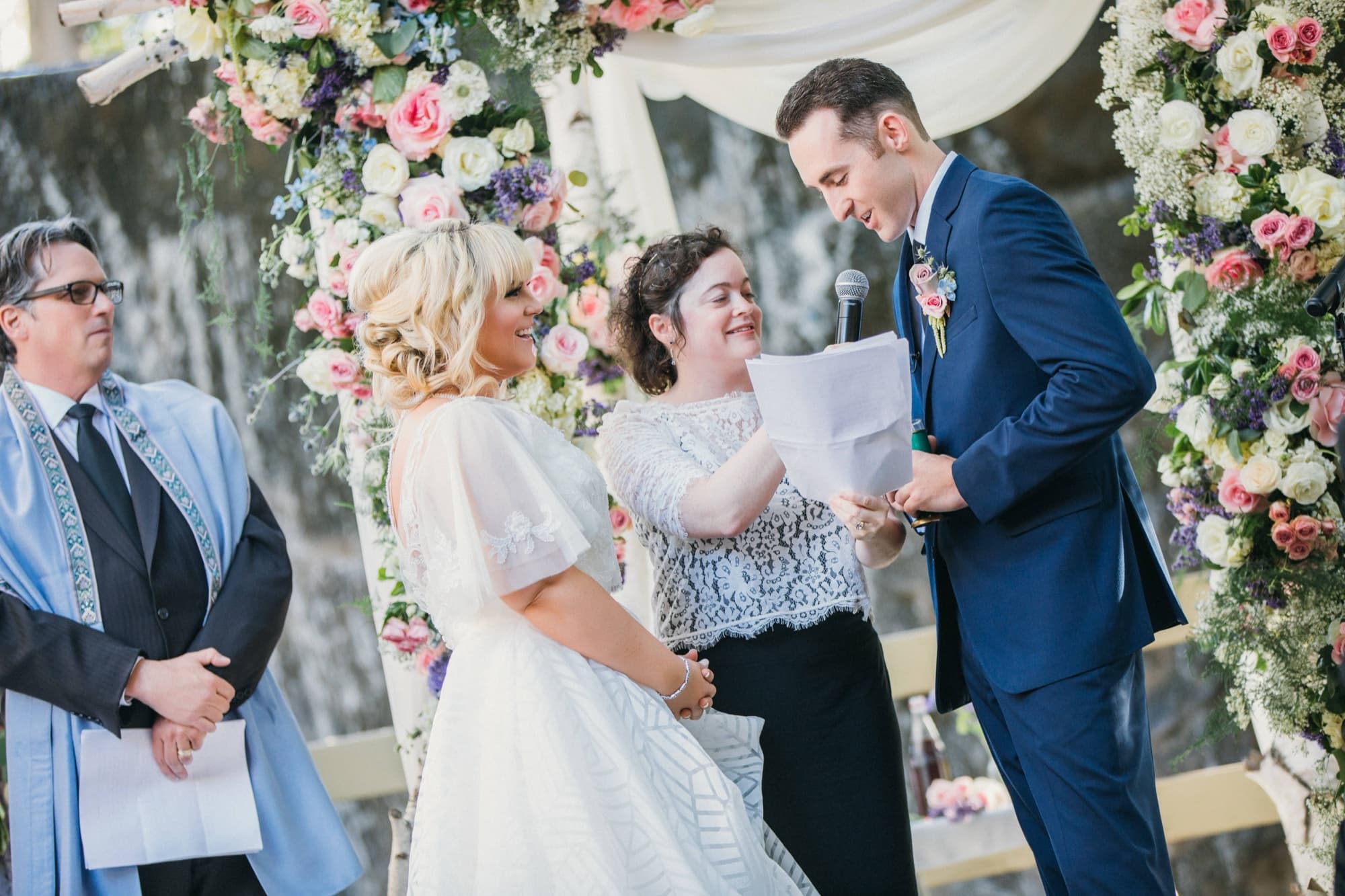 Stephanie and Grant exchanging vows beneath the pastel floral arch at the Calamigos Ranch waterfall ceremony site