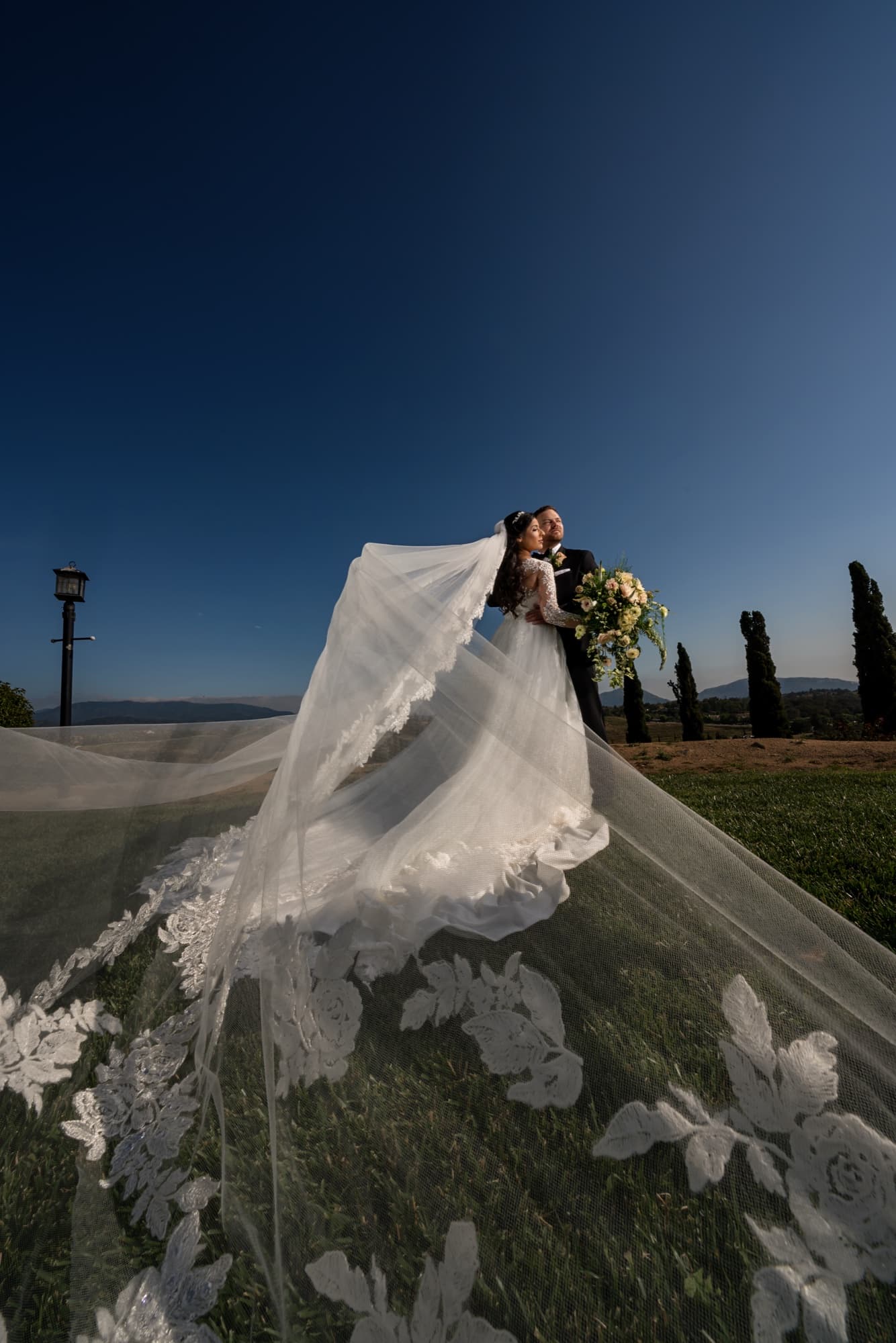 Tania's floral cathedral veil flying across the vineyard rows at golden hour with Cole at Callaway in Temecula