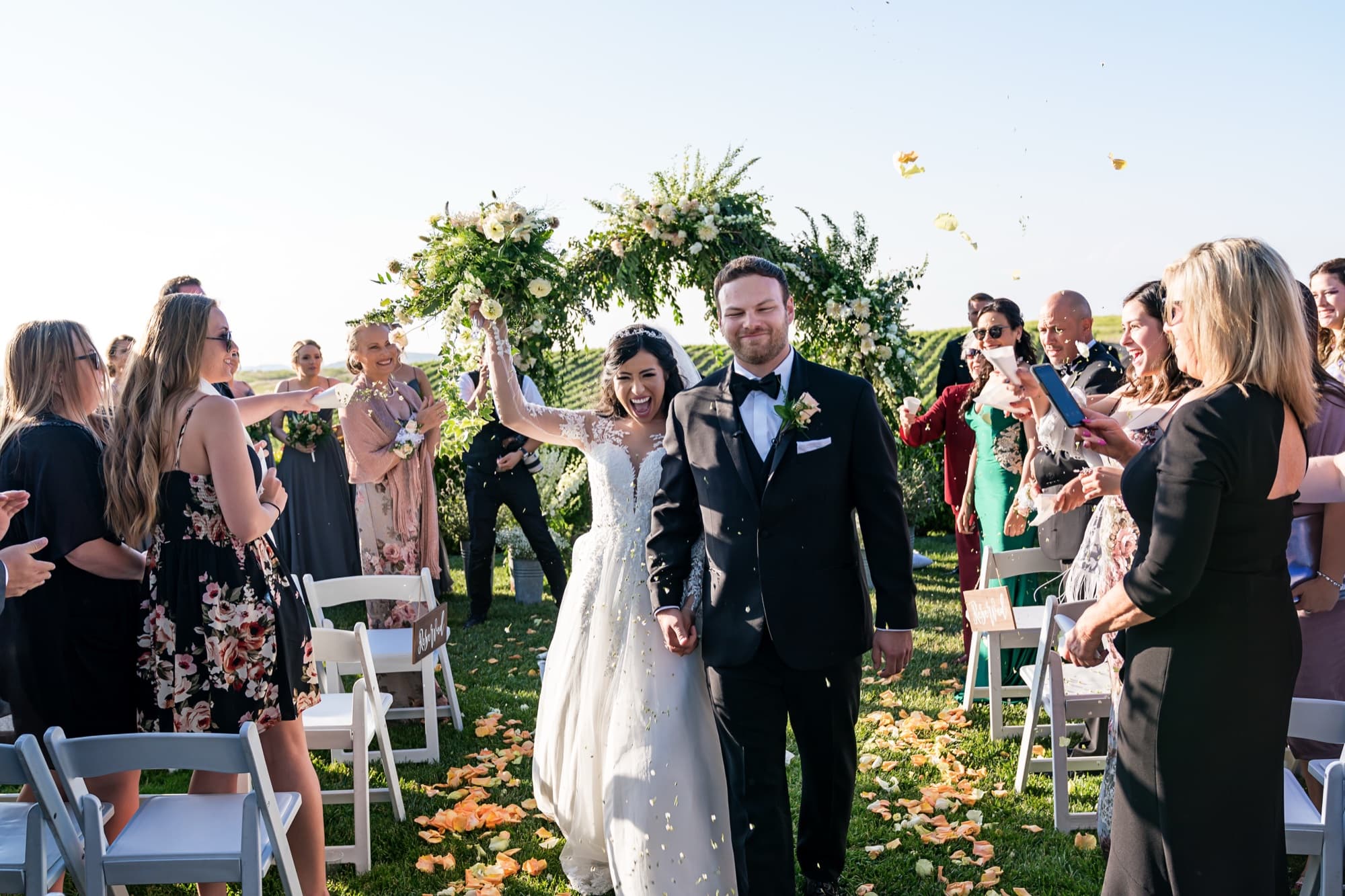 Tania and Cole celebrating in a shower of petals as they walk back up the aisle at their Callaway Vineyard wedding