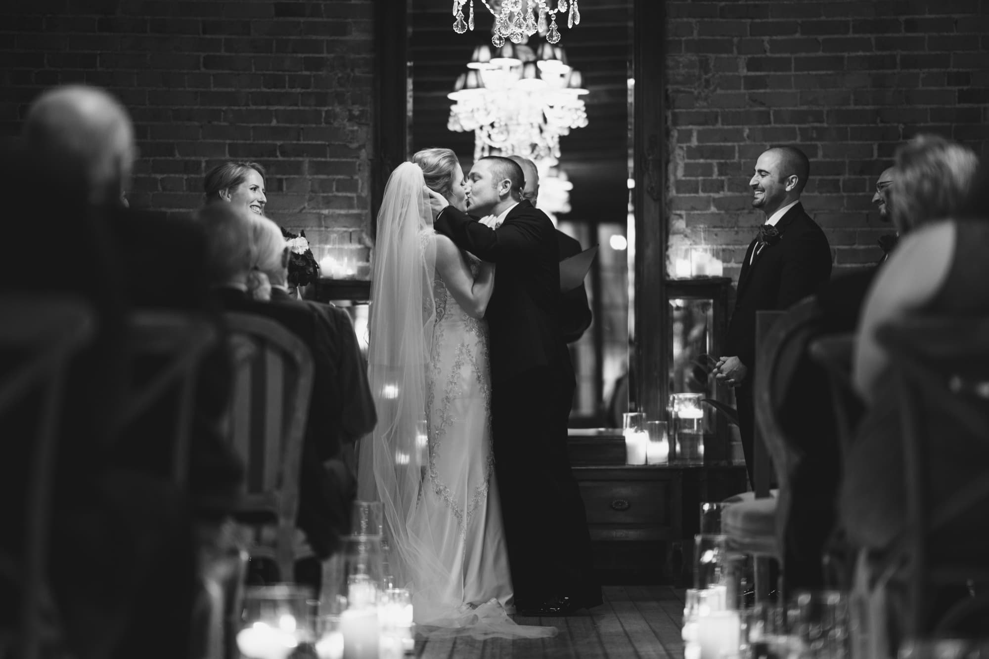 Black and white photograph of Briana's first kiss with Peter during their candlelit ceremony at Carondelet House