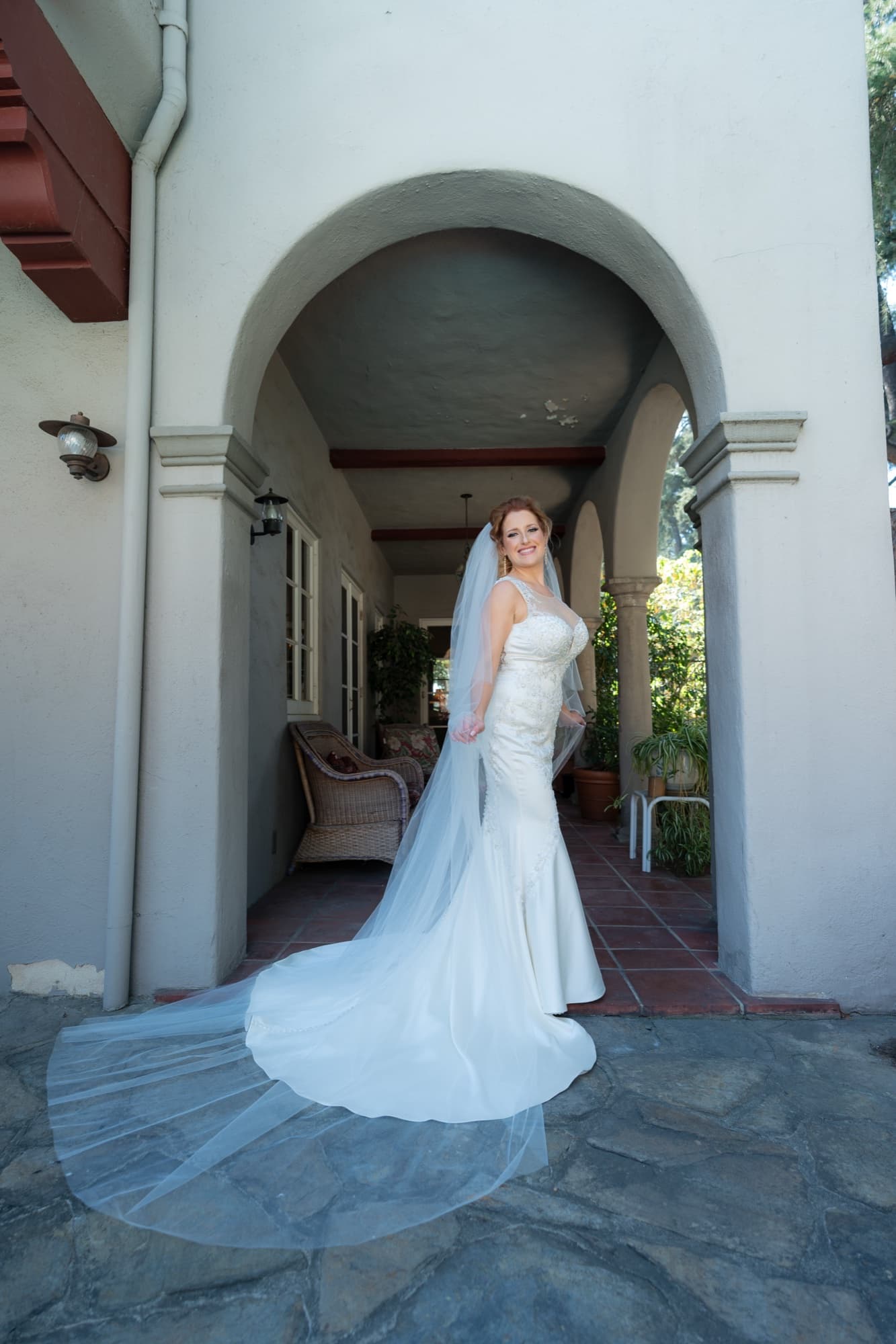 Briana with her cathedral train fanned across the flagstone under the whitewashed Spanish arcade at Carondelet House