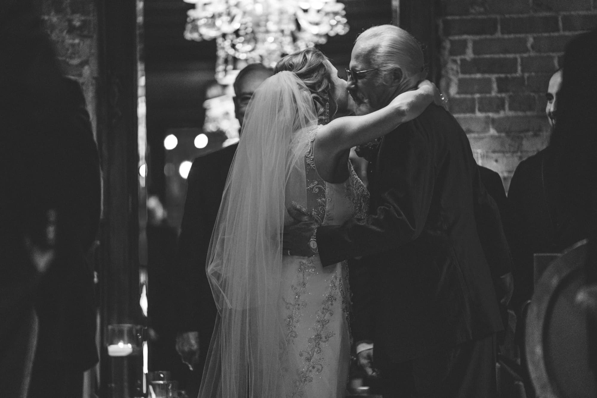Black and white photograph of Briana dancing with her father under the chandeliers at Carondelet House