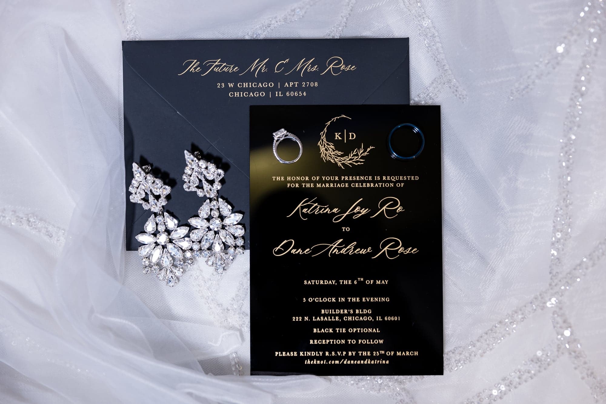 Katrinia and Dane's black-and-gold invitation with rings and crystal earrings