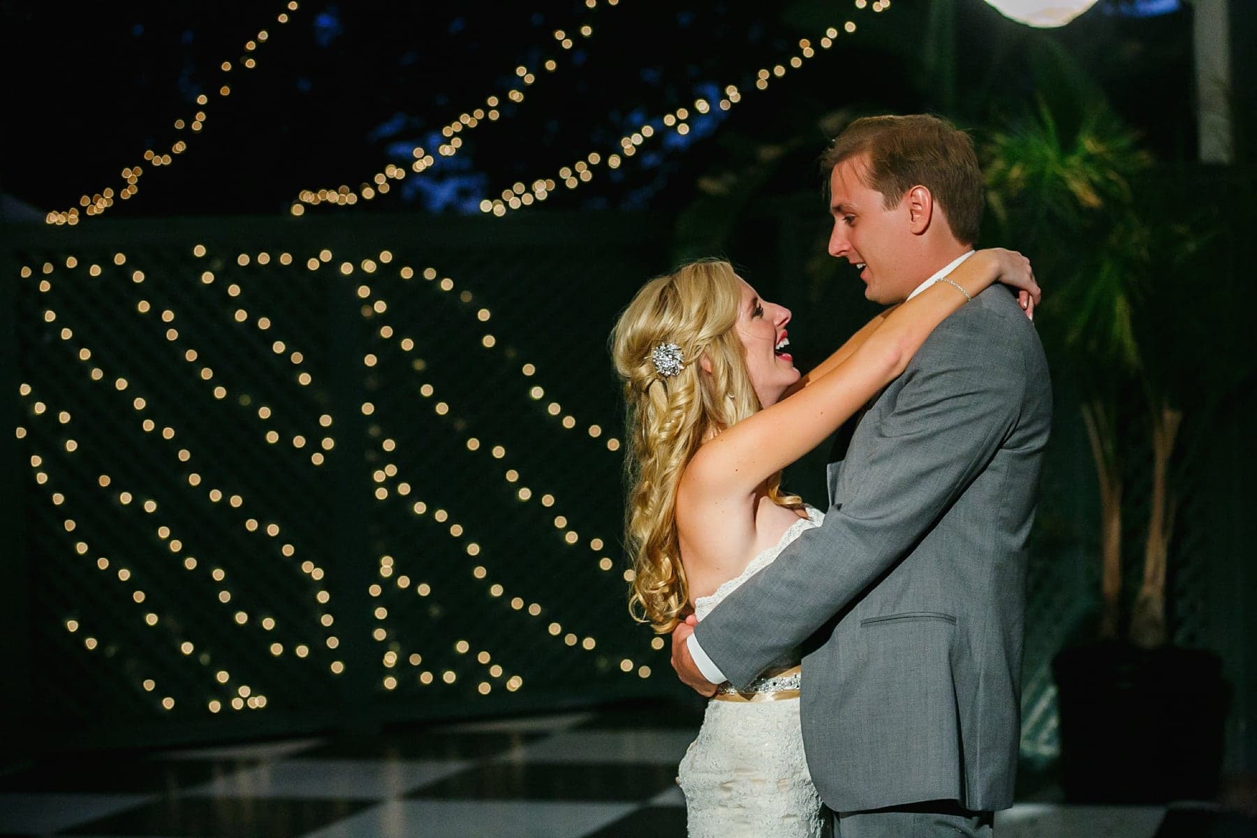 Newlyweds dancing beneath string lights