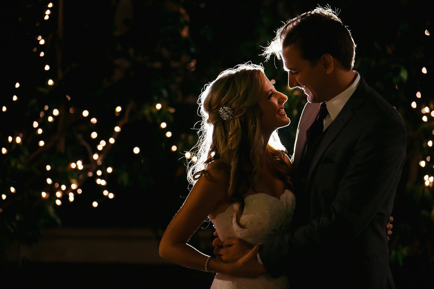 Newlyweds beneath the illuminated reception trees