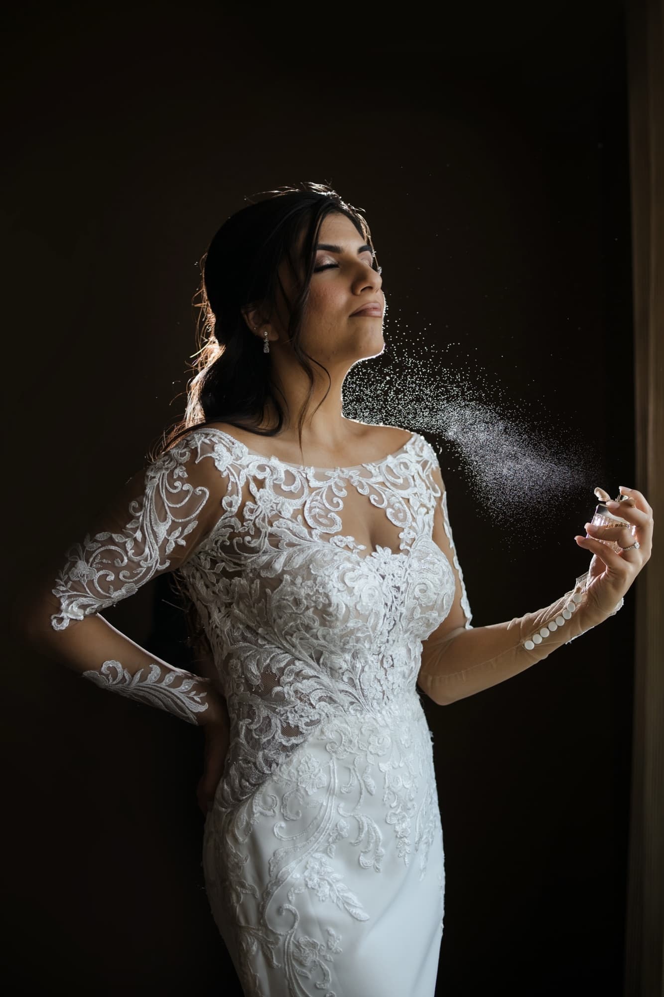 Hela spritzing perfume in her lace gown, backlit dramatically by the window