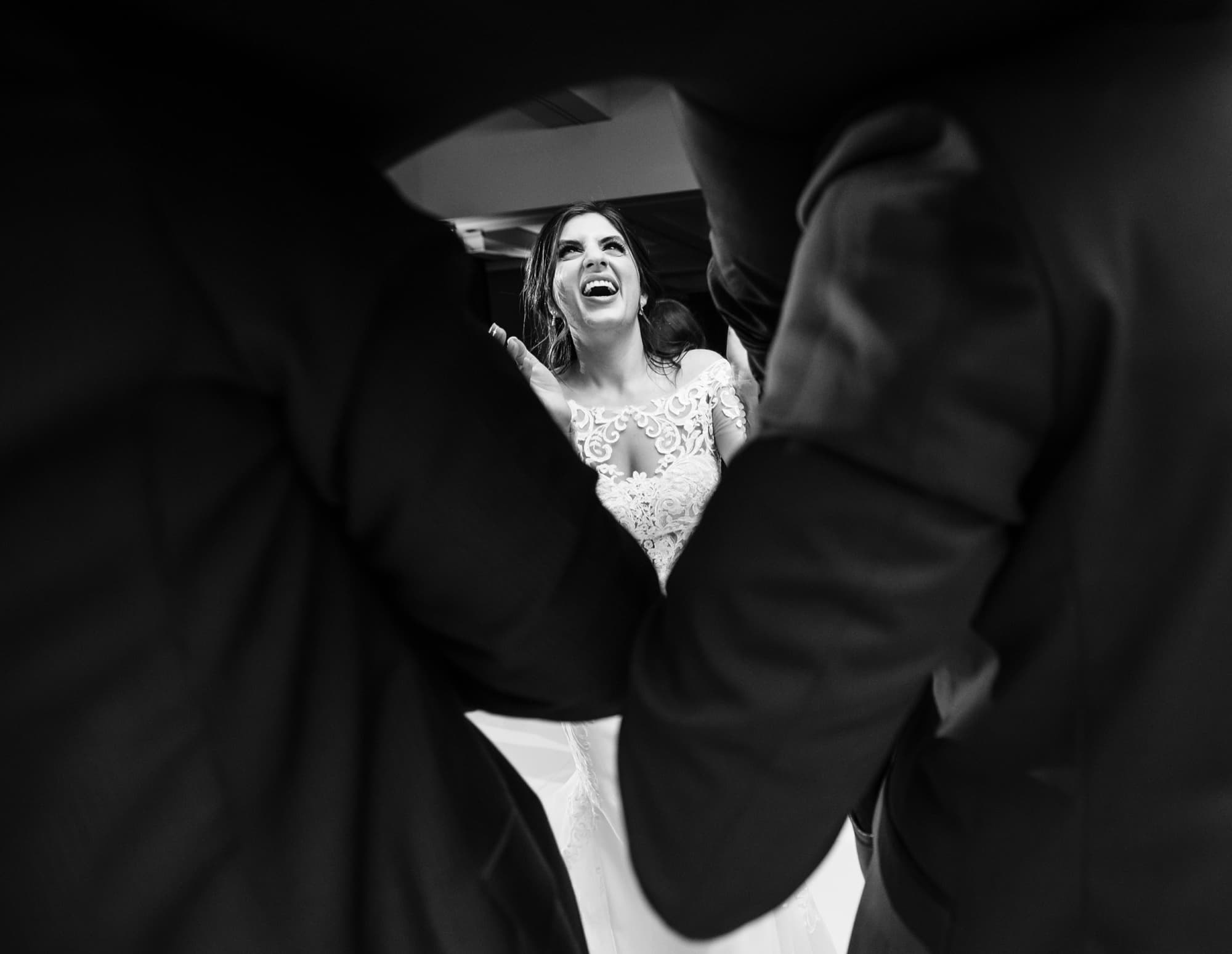 Black and white photograph of Hela laughing over Yousef's shoulder in the middle of the dance floor