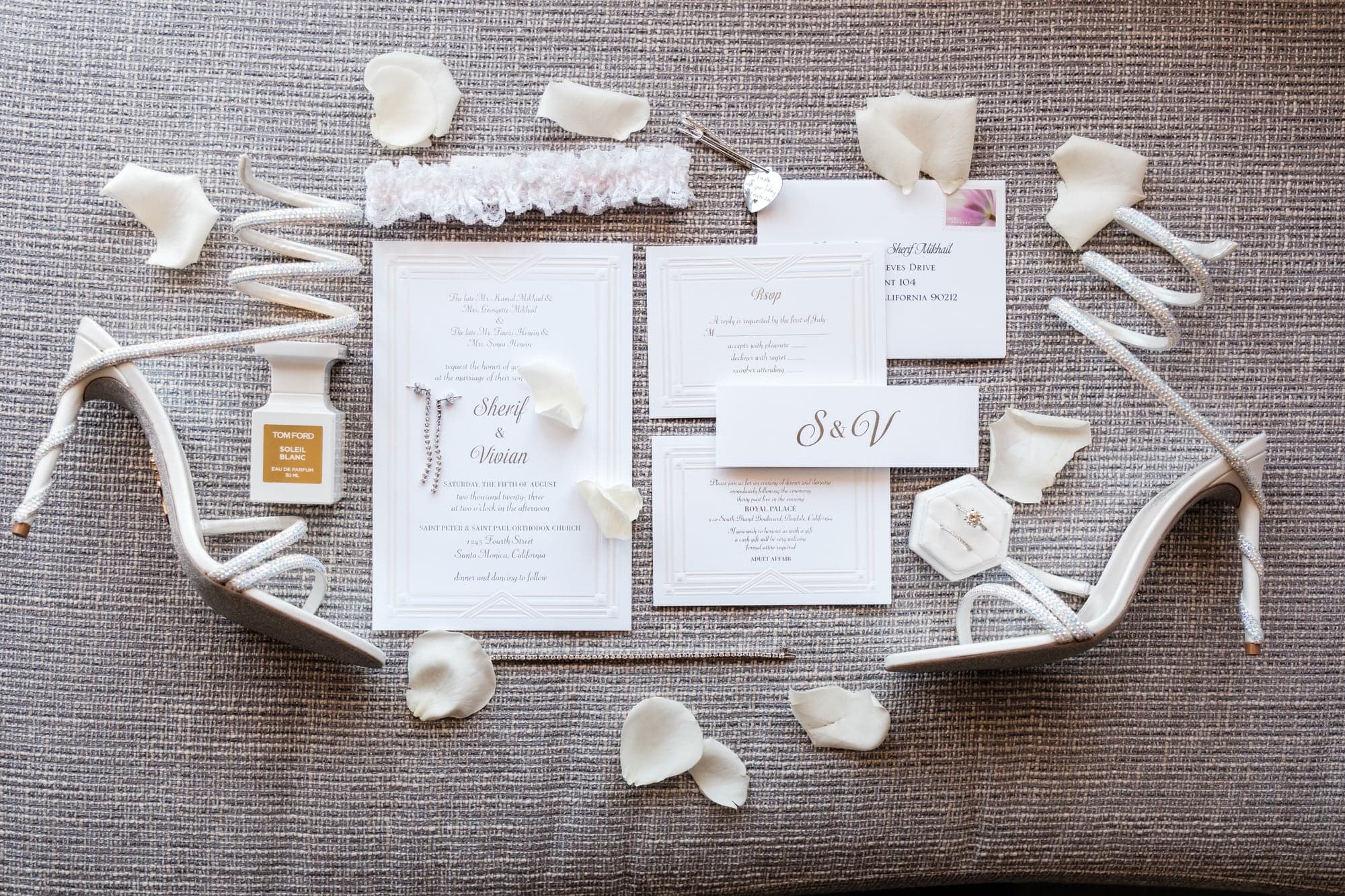 Vivian and Sherif's stationery, rings, shoes, and white flowers arranged before the wedding