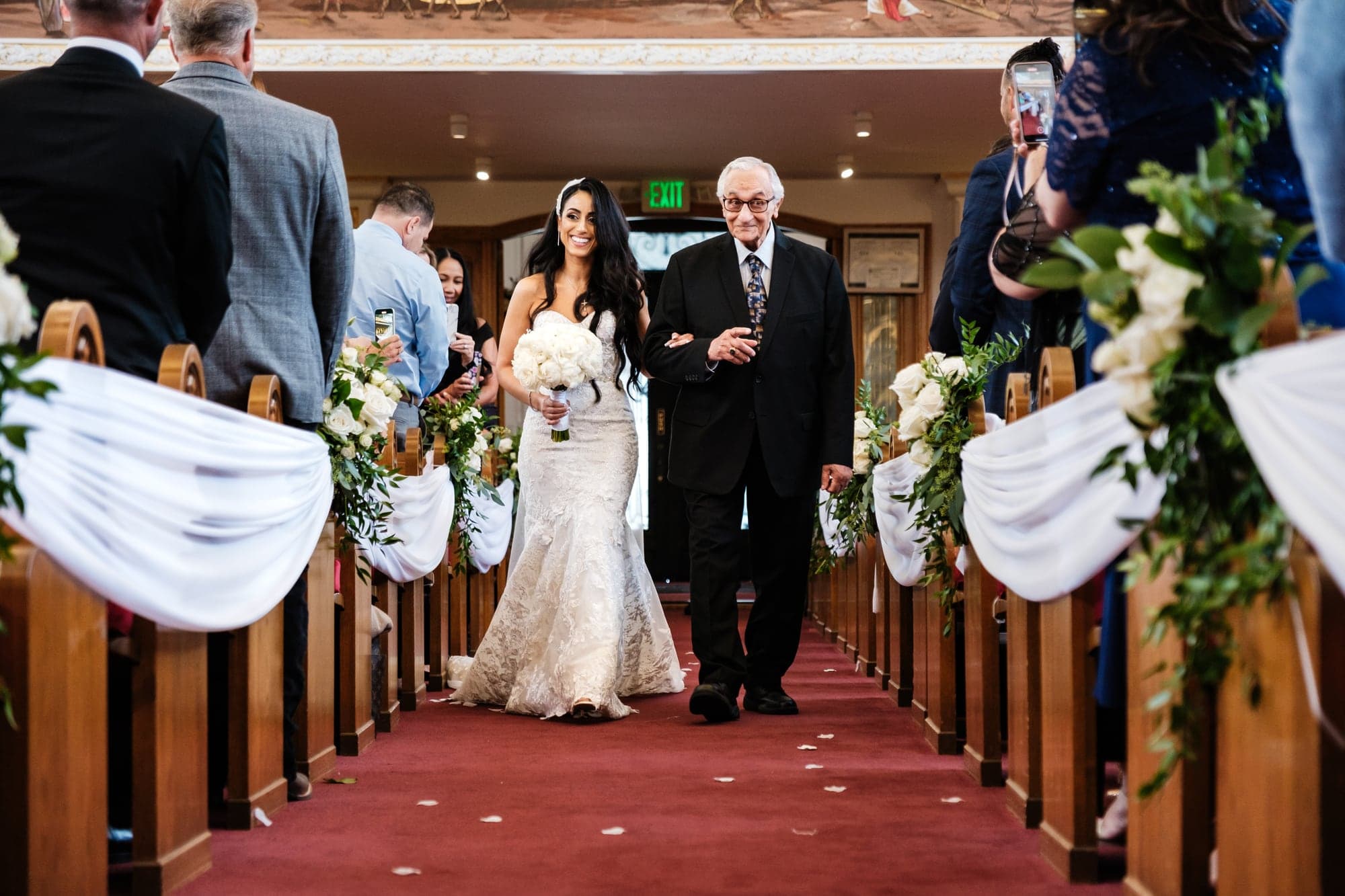 Vivian walking down the red church aisle with family during the processional