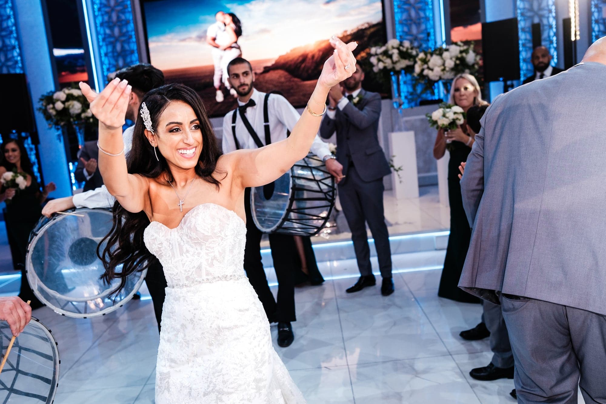 Vivian and Sherif celebrating on a blue-lit dance floor surrounded by guests