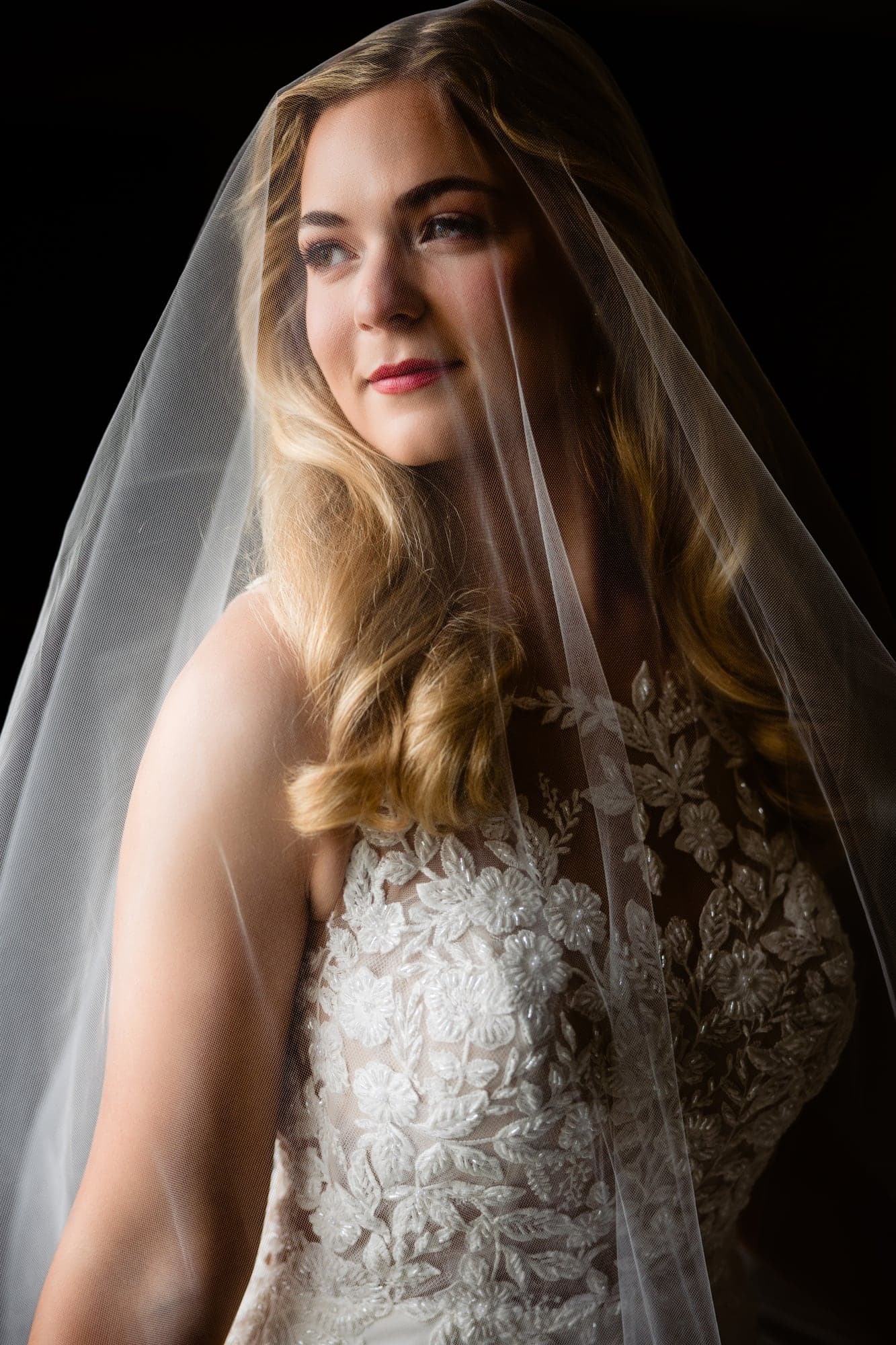 Lindsay standing in soft window light in her wedding dress before the Dallas ceremony