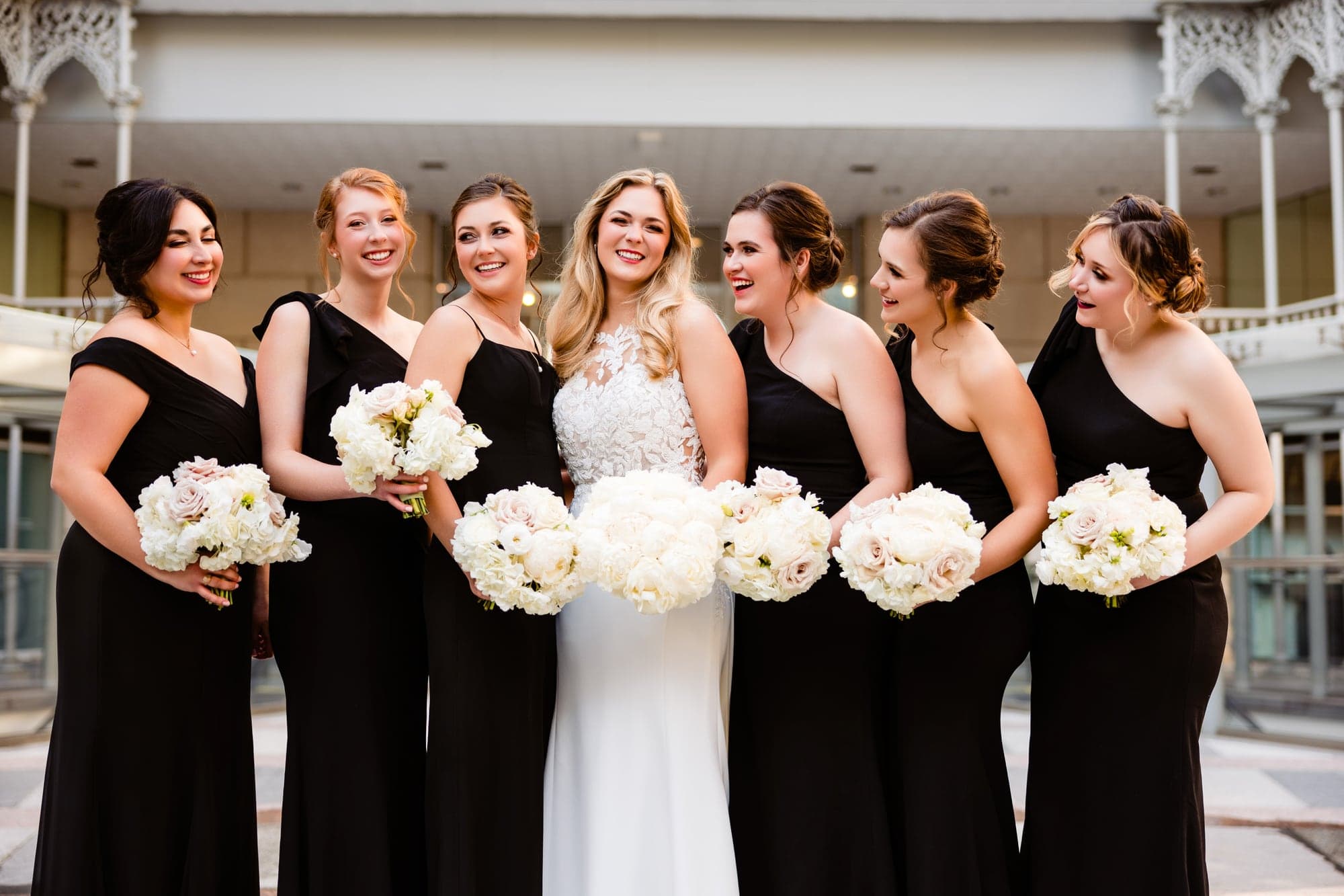 The wedding party gathered beside modern glass architecture in downtown Dallas