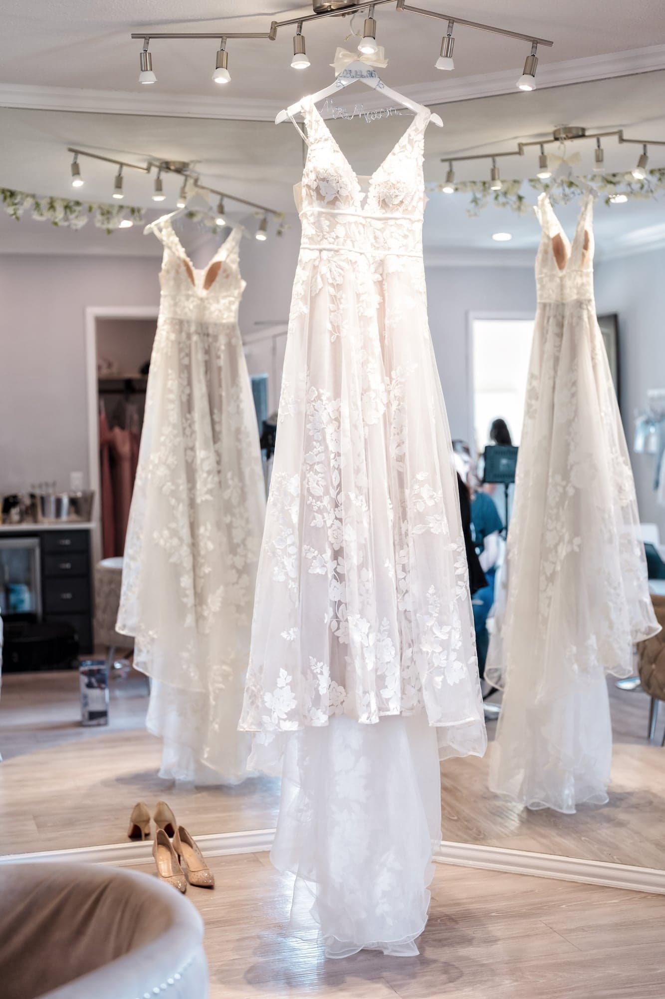 Erin's floral lace gown hanging in the bridal suite between two other dresses