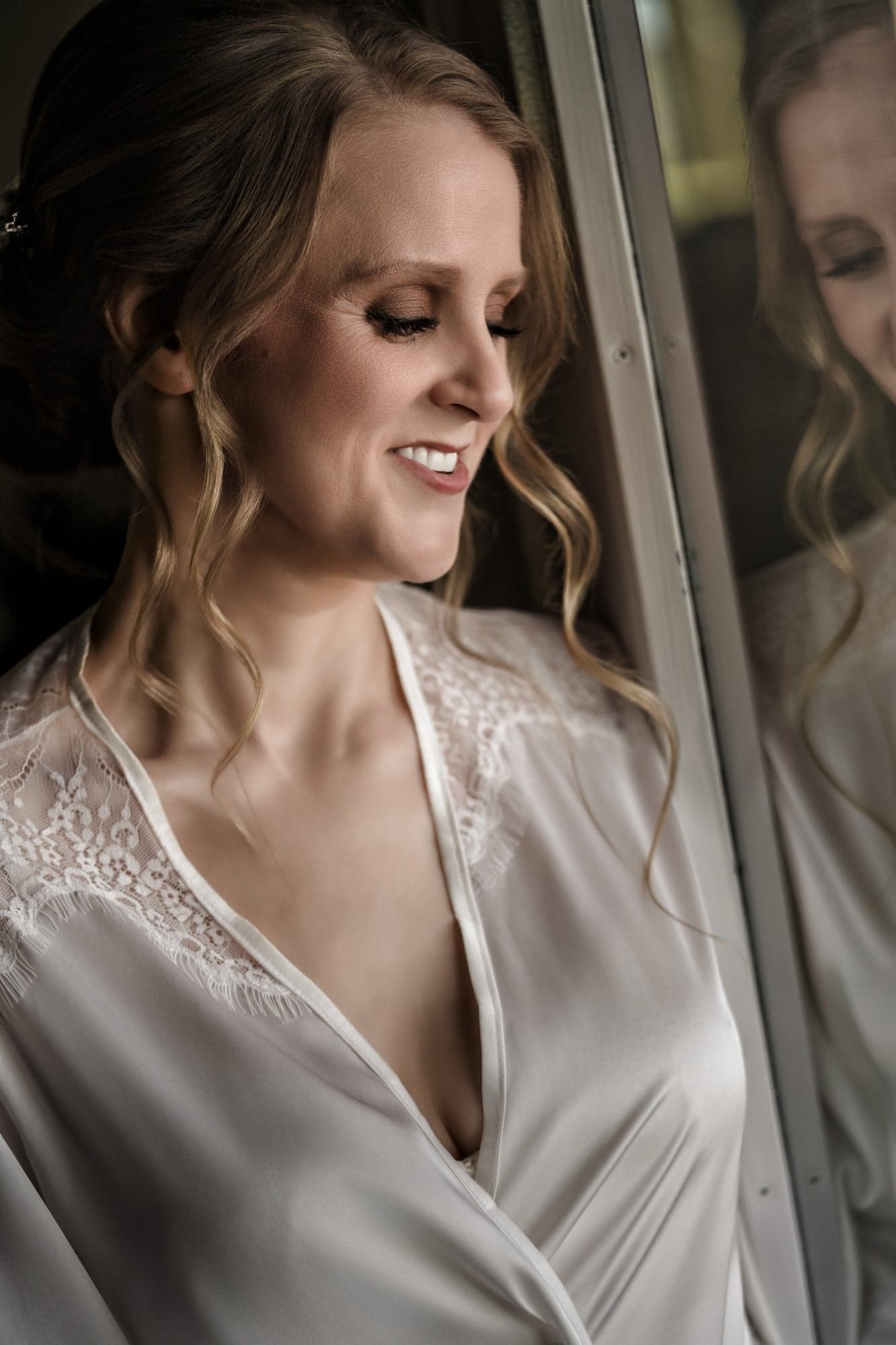 Erin in her ivory robe in window light during hair and makeup