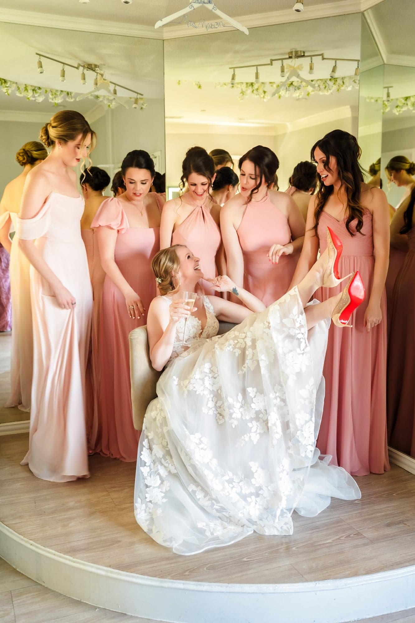 The bridesmaids in blush gowns gathered around Erin as she gets into her dress