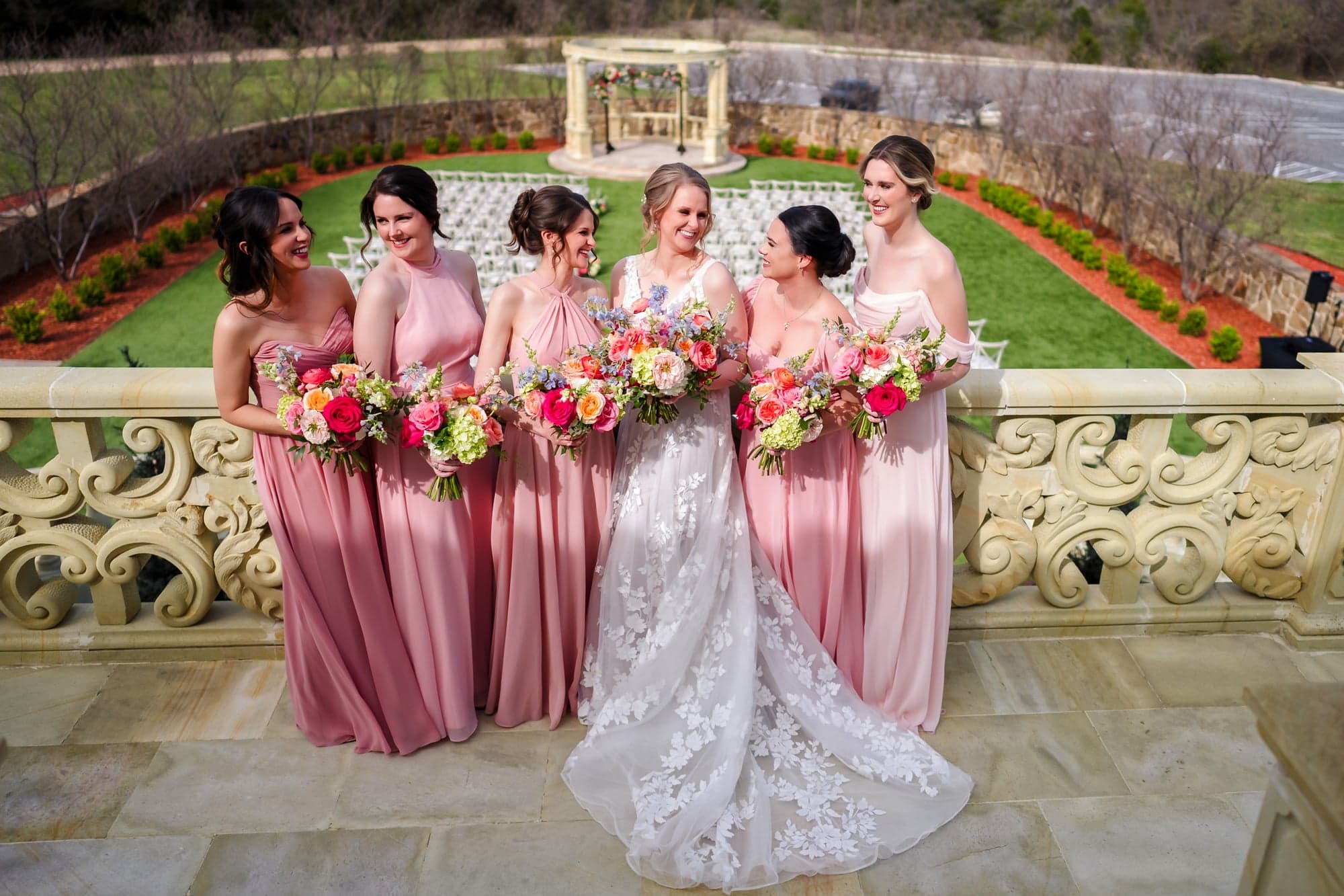 Erin and her five bridesmaids in blush gowns along the stone balustrade above the ceremony lawn