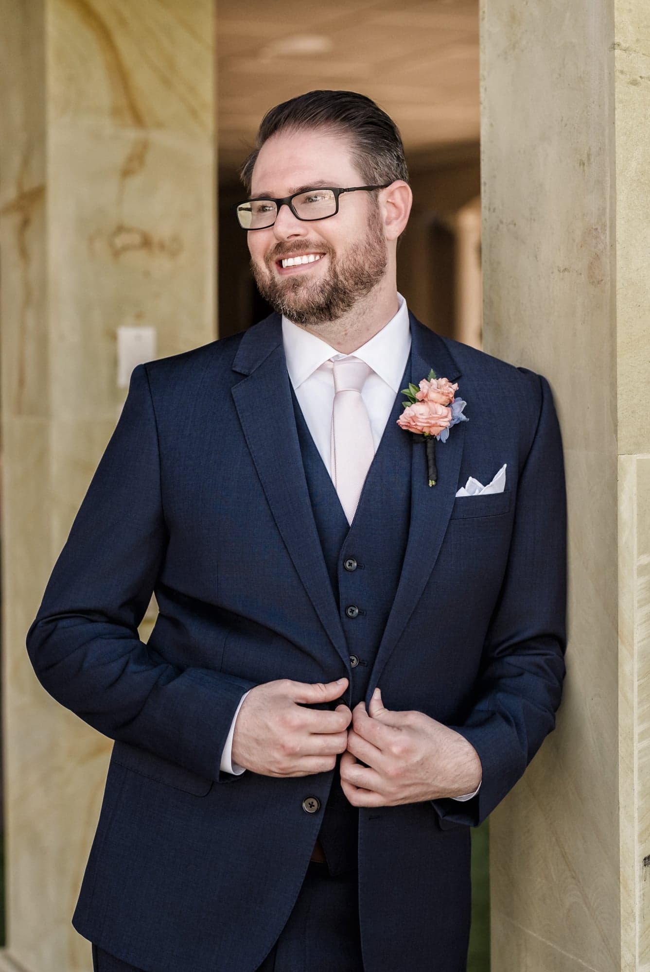 Hunter buttoning his navy jacket in the shaded stone arcade at D'Vine Grace Vineyard