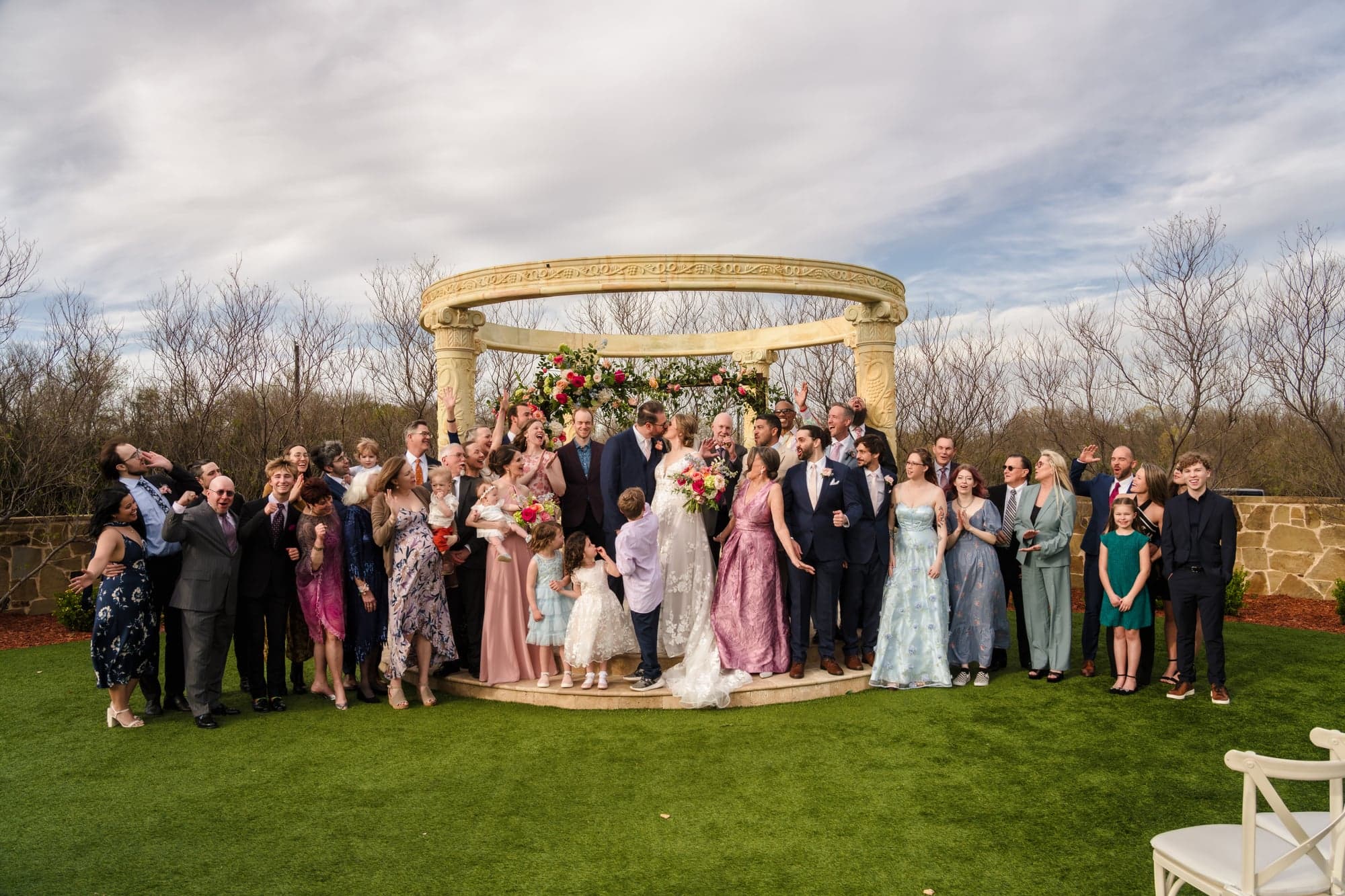 Every guest gathered around Erin and Hunter at the rotunda for a group portrait under a cloudy sky