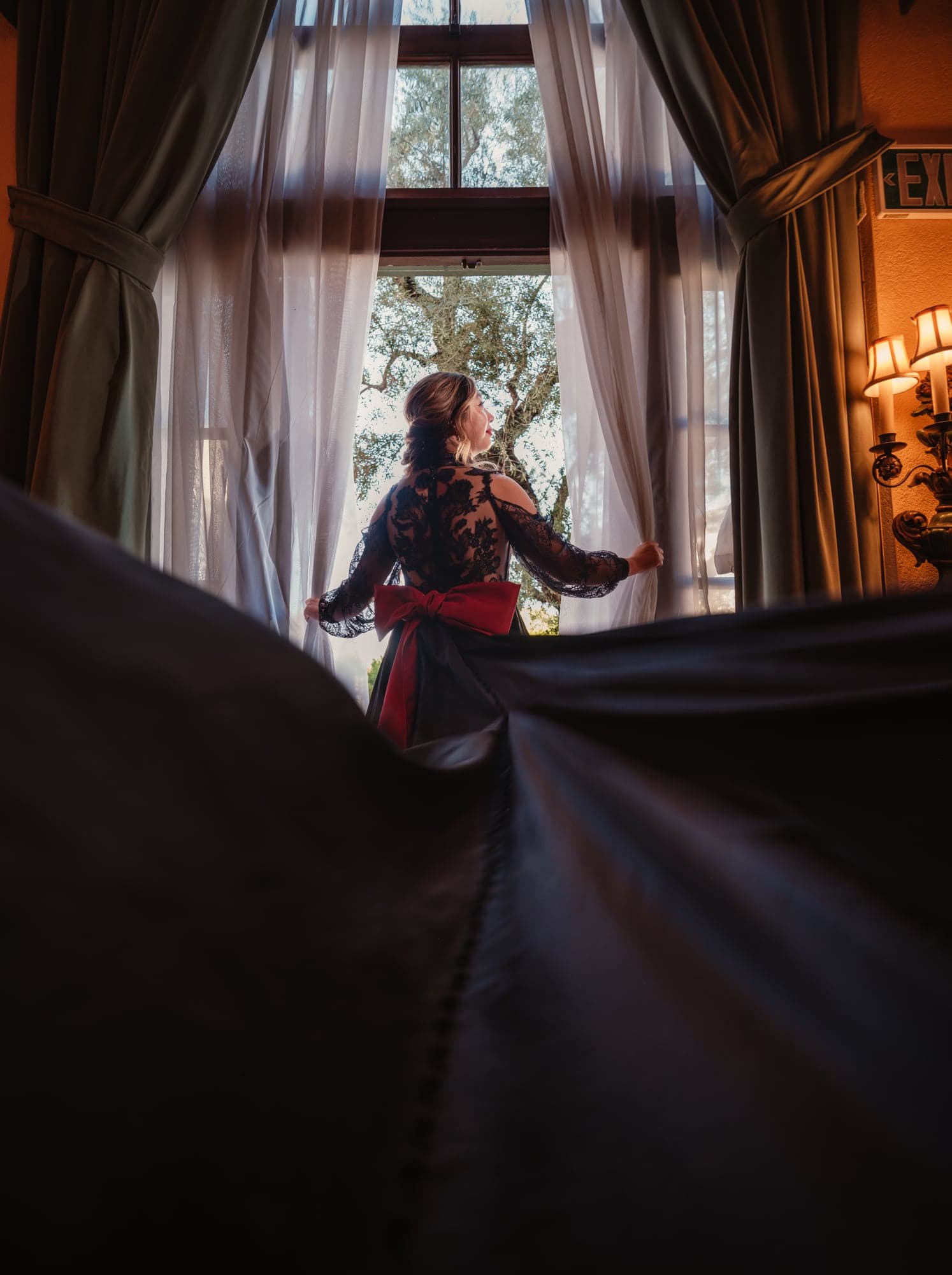 Alda walking through window light as her black gown moves