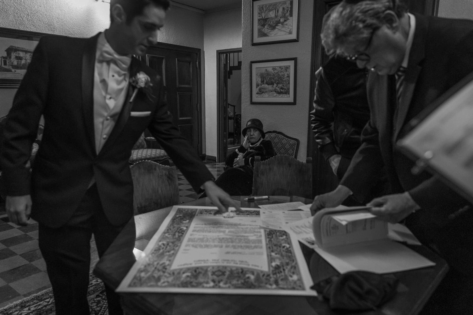 Black and white photograph of the ketubah being signed in the club rooms before the Ebell ceremony