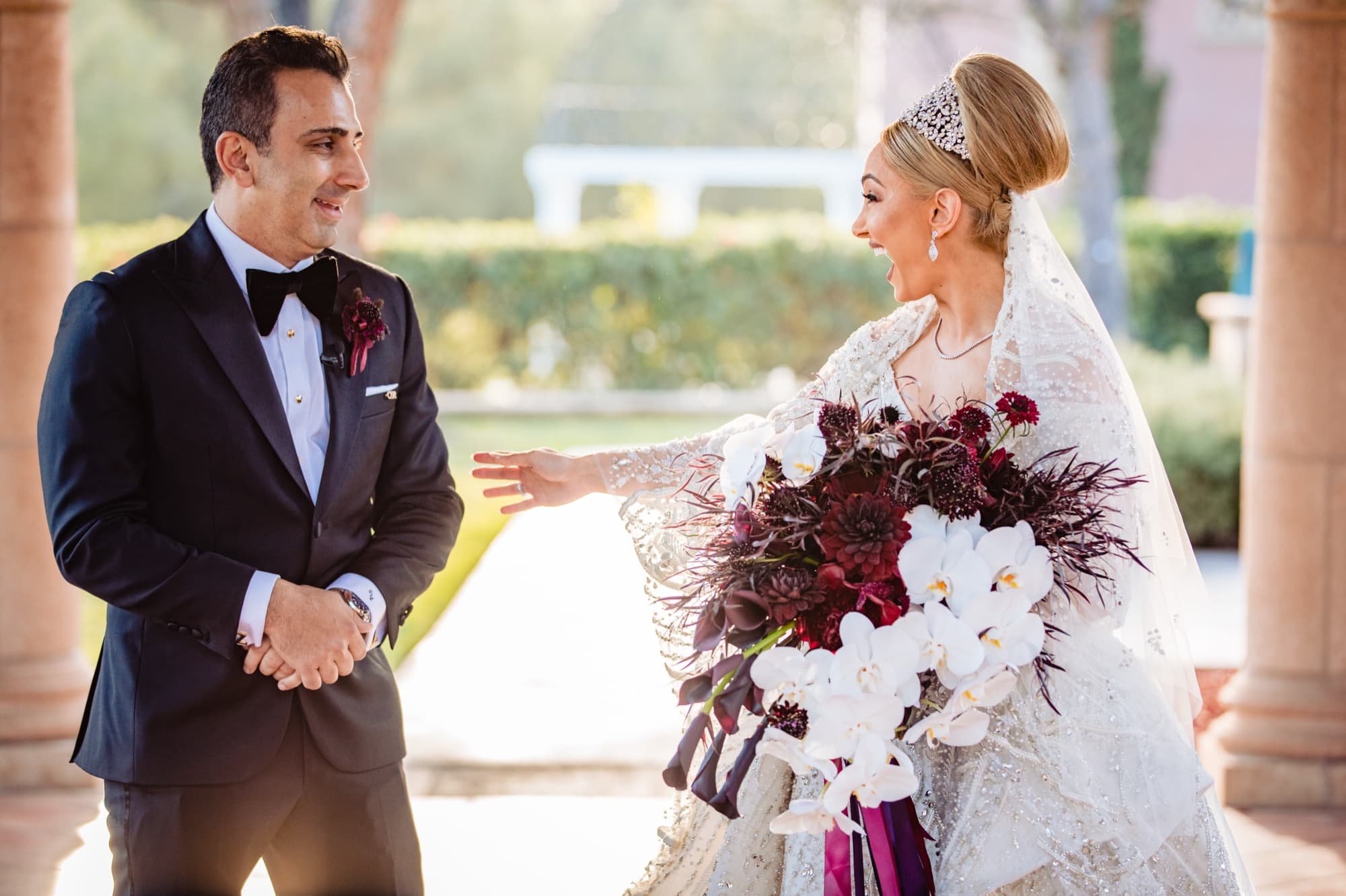 Christopher reaching for Rhonda during their first look in the garden arcade of the Fairmont Grand Del Mar