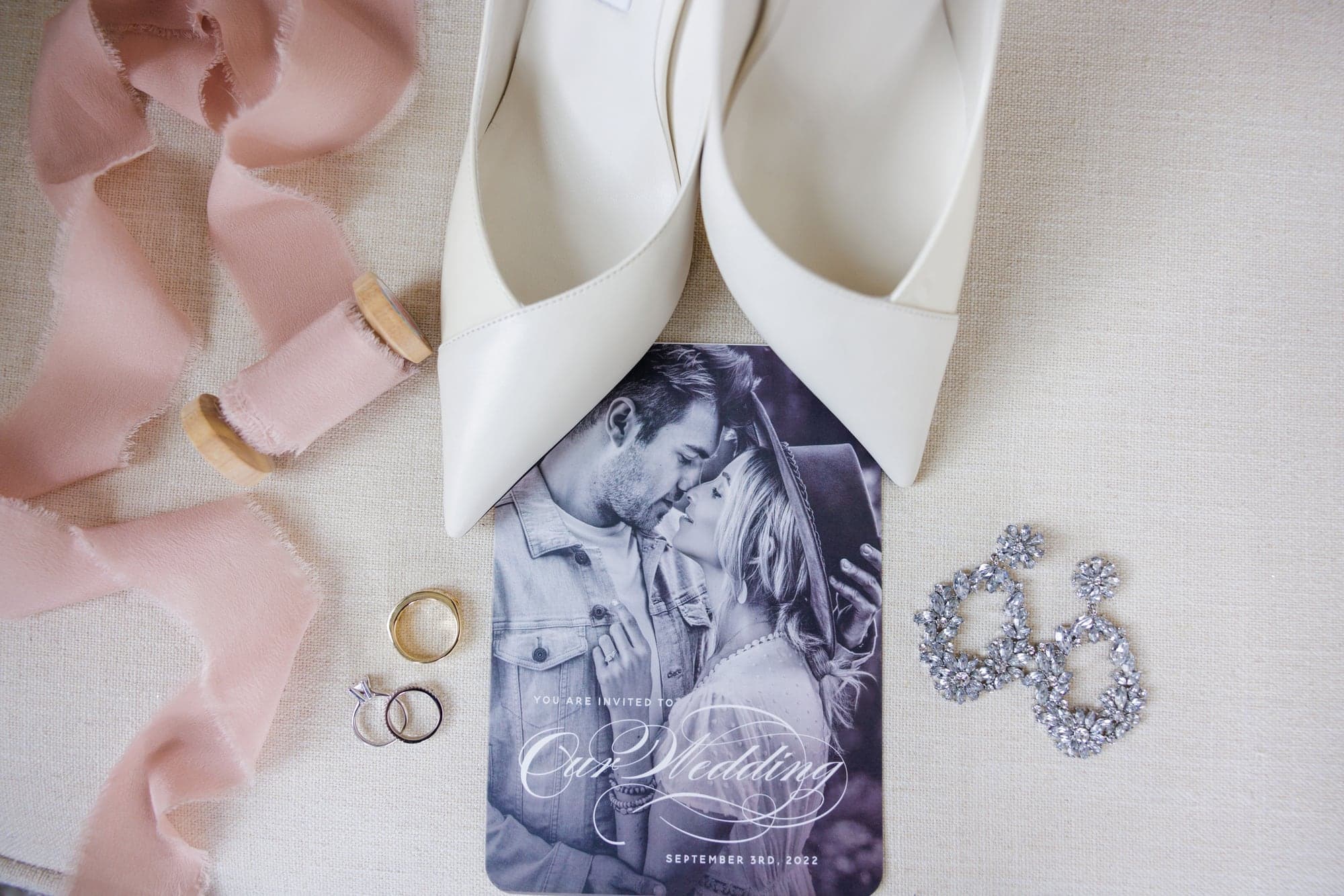 Amber's pale blue wedding details, jewelry, and invitation arranged at Fiddle Dee Farms