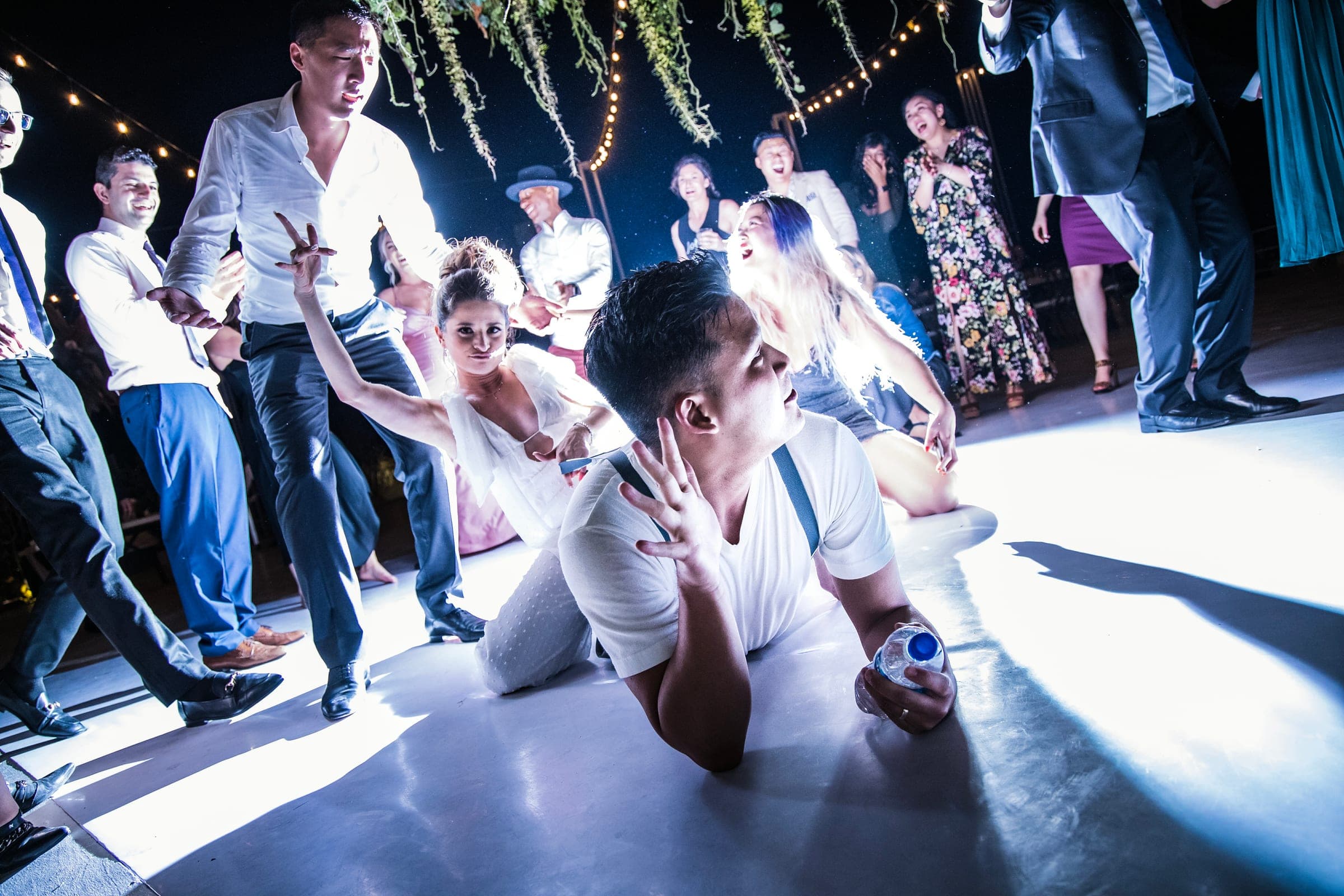 Guests packed onto a dark dance floor under string lights, caught mid-motion.