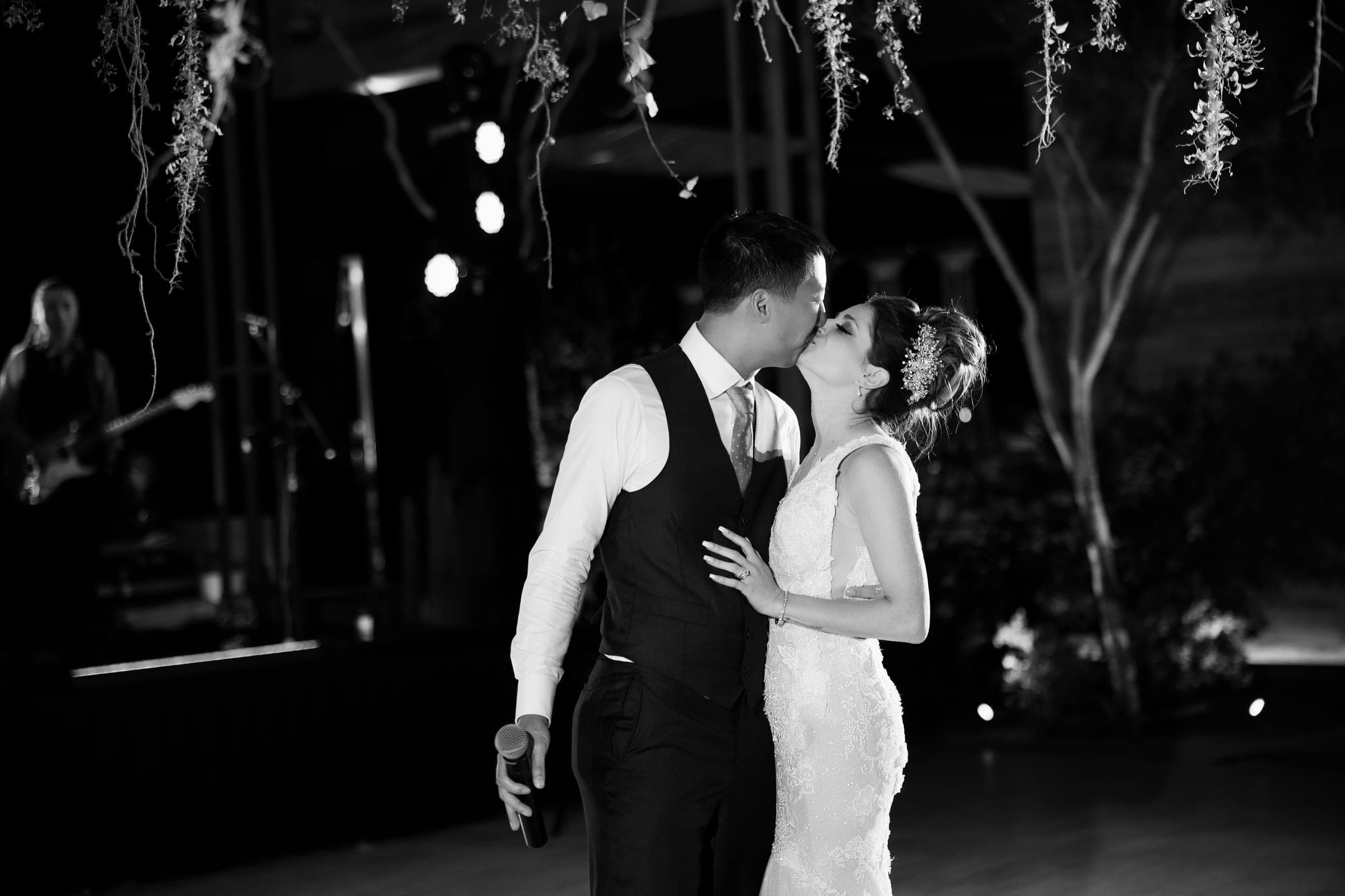 A couple dancing close in a darkened reception room, lit only by the venue low light, the kind of frame a roll of film cannot hold after sunset.