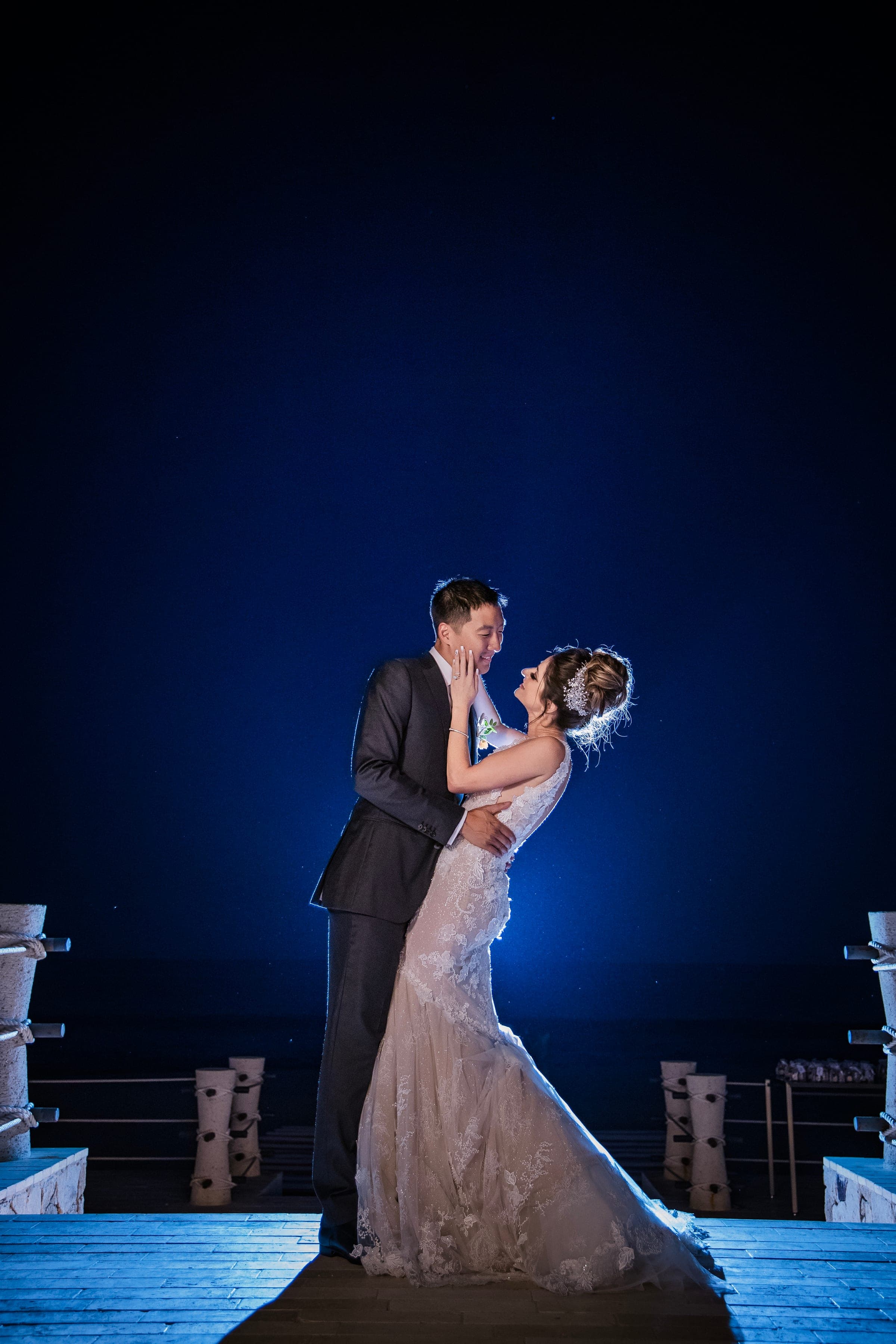 A couple dancing under deep blue light late in the reception, the room dark behind them.