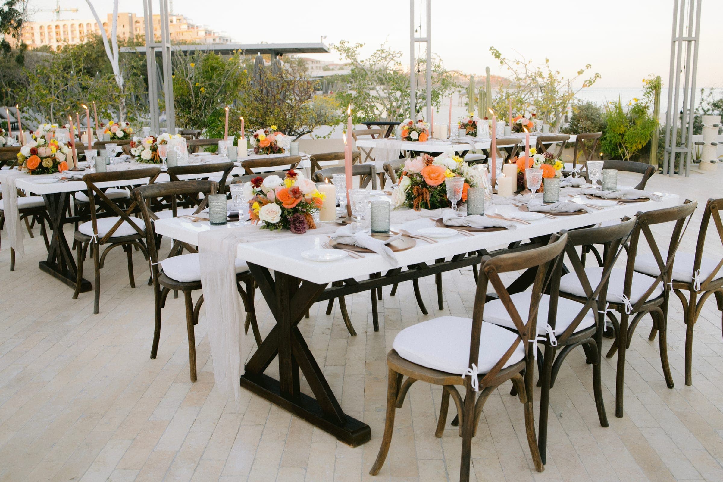 Long reception tables set with candles and low florals before guests are seated.
