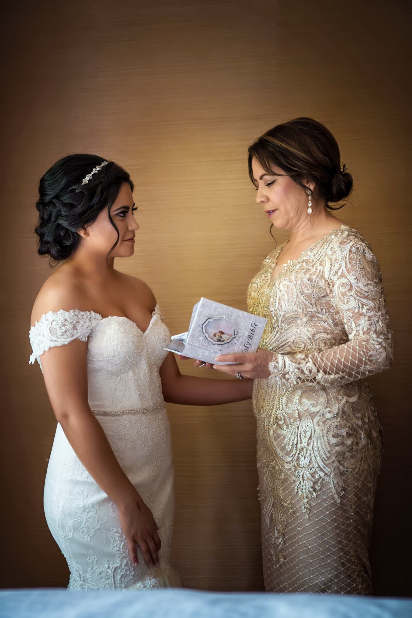 Bride and her mother in gold beaded lace reading a prayer book together before the wedding ceremony