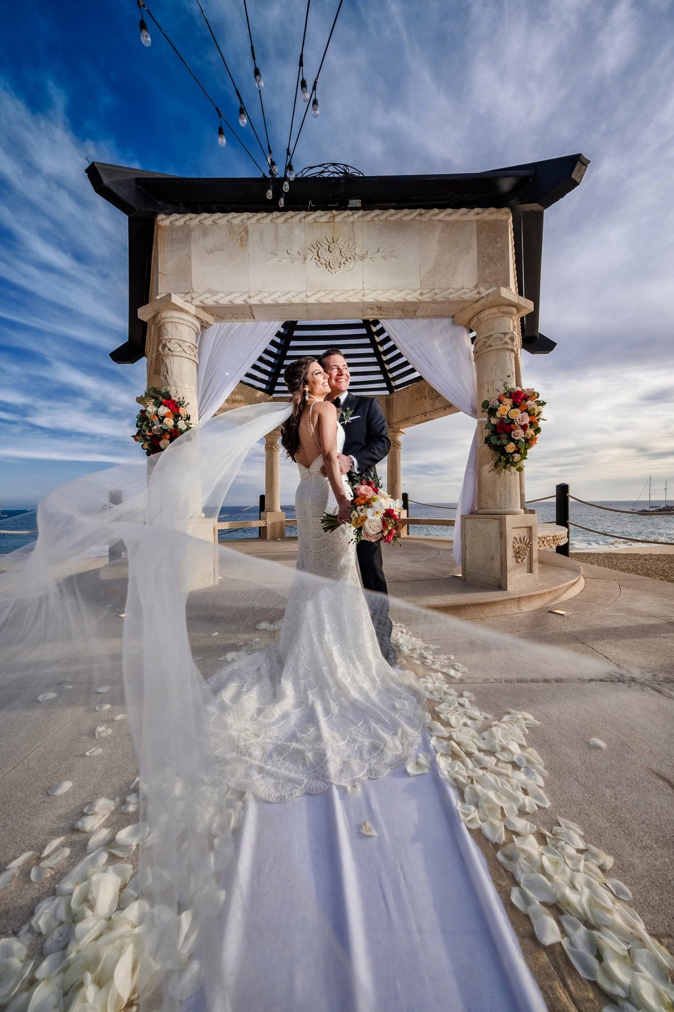 Tina and David beneath the Grand Solmar ceremony canopy with her veil trailing toward the sea